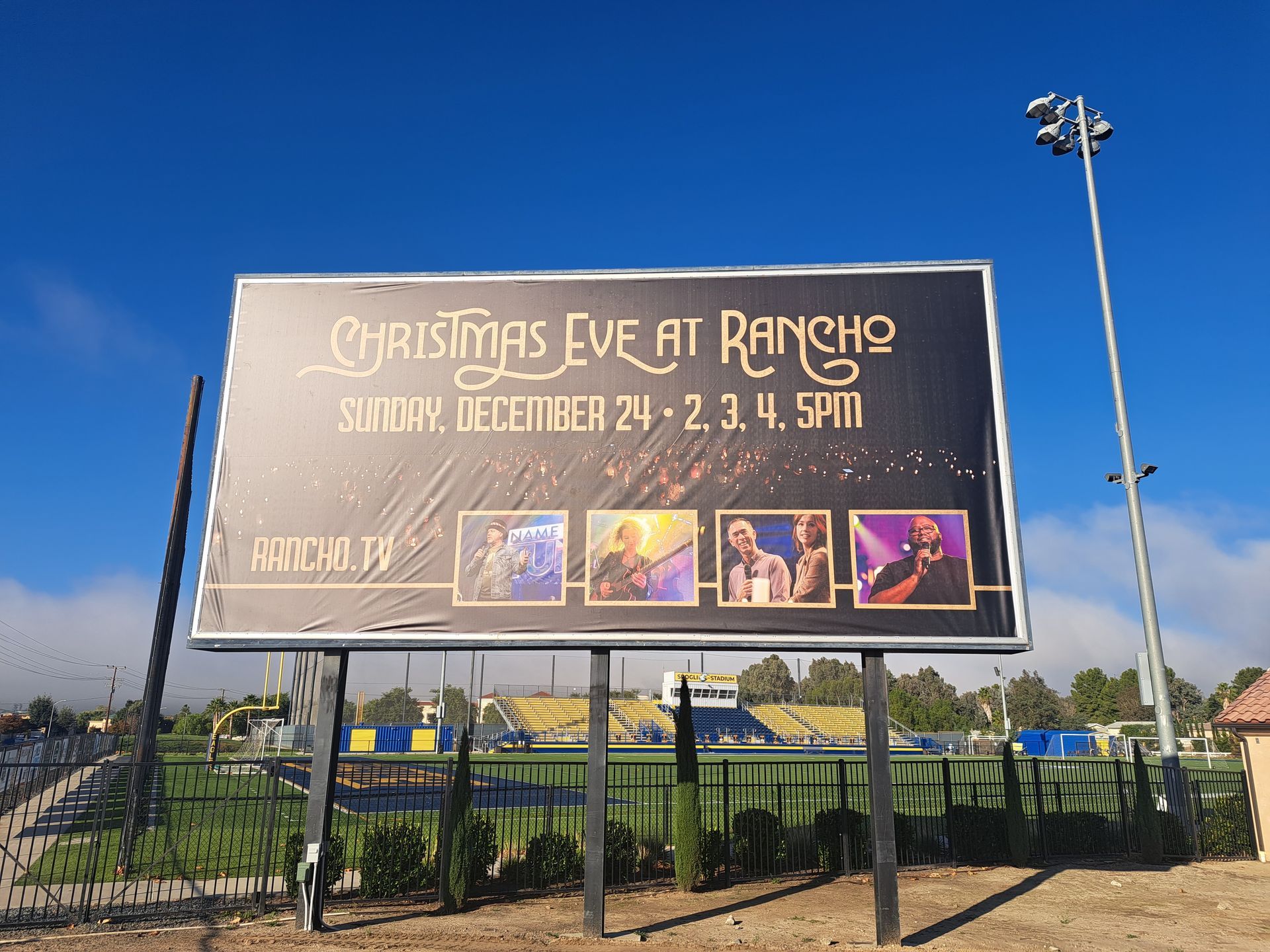 Billboard for “Christmas Eve at Rancho,” with event dates and performer photos against a blue sky.