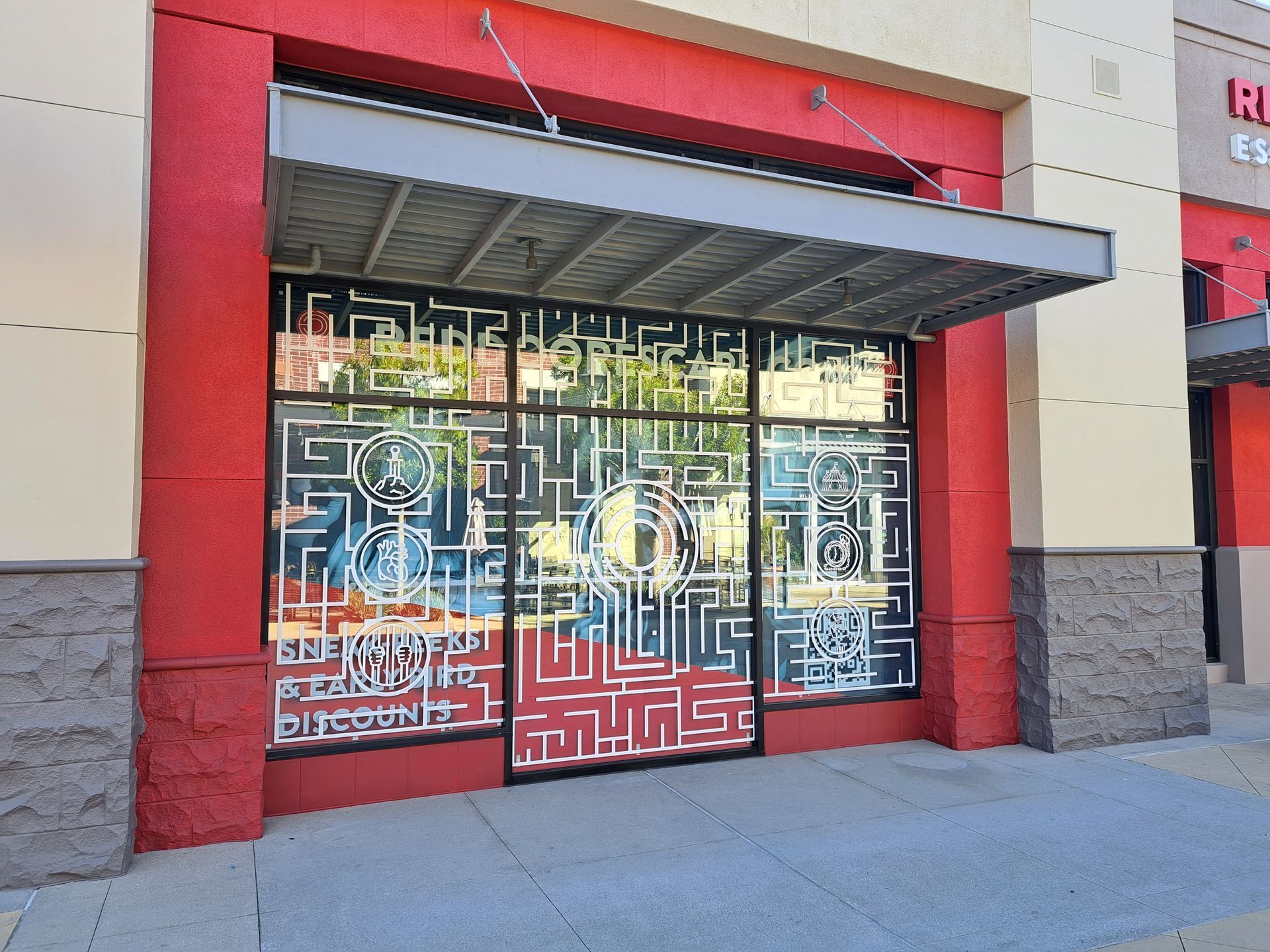 Storefront with red facade, geometric glass doors, and a metal awning at the entrance
