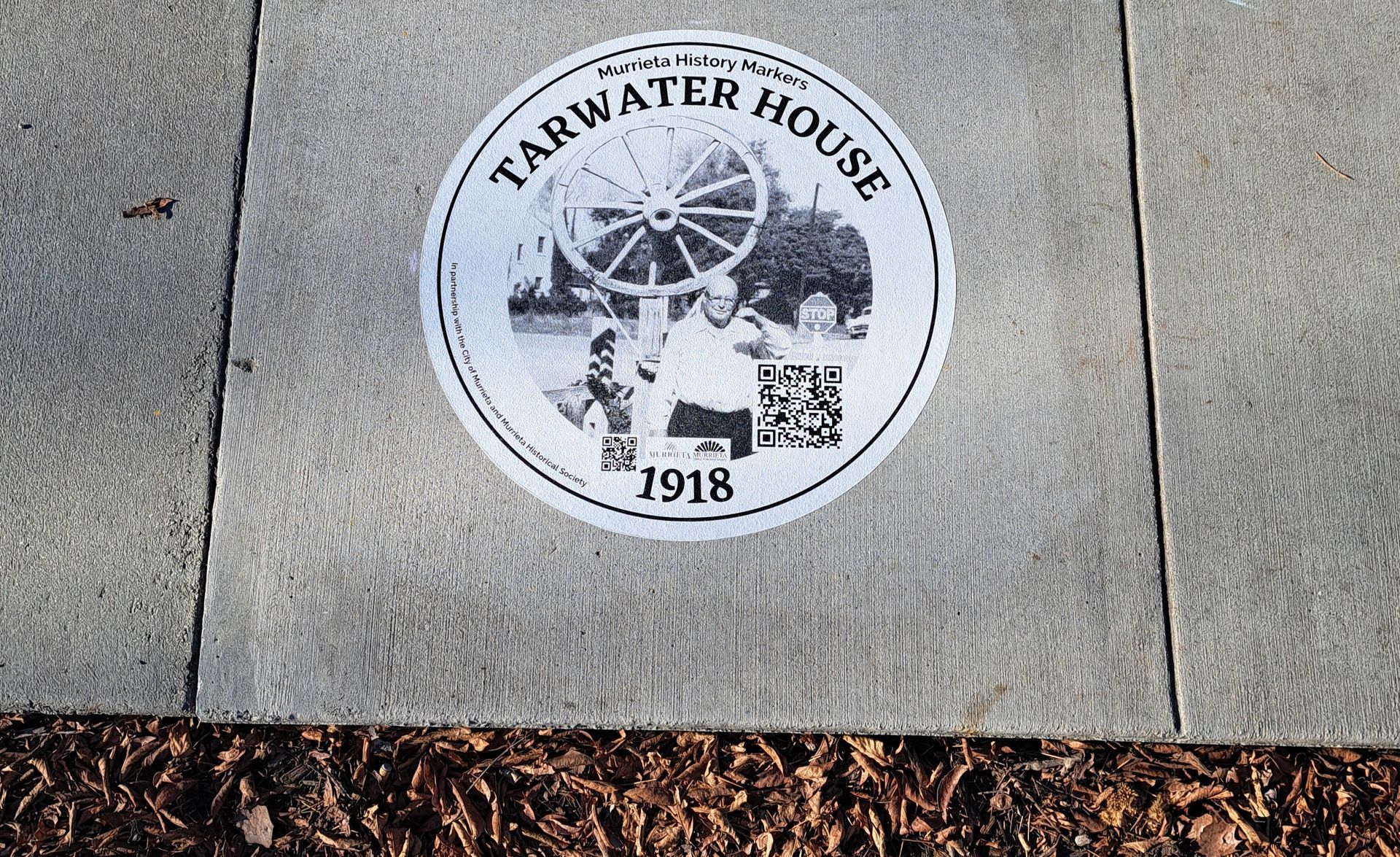 Farwater House commemorative sidewalk medallion with Ferris wheel and “1918” on concrete pavement