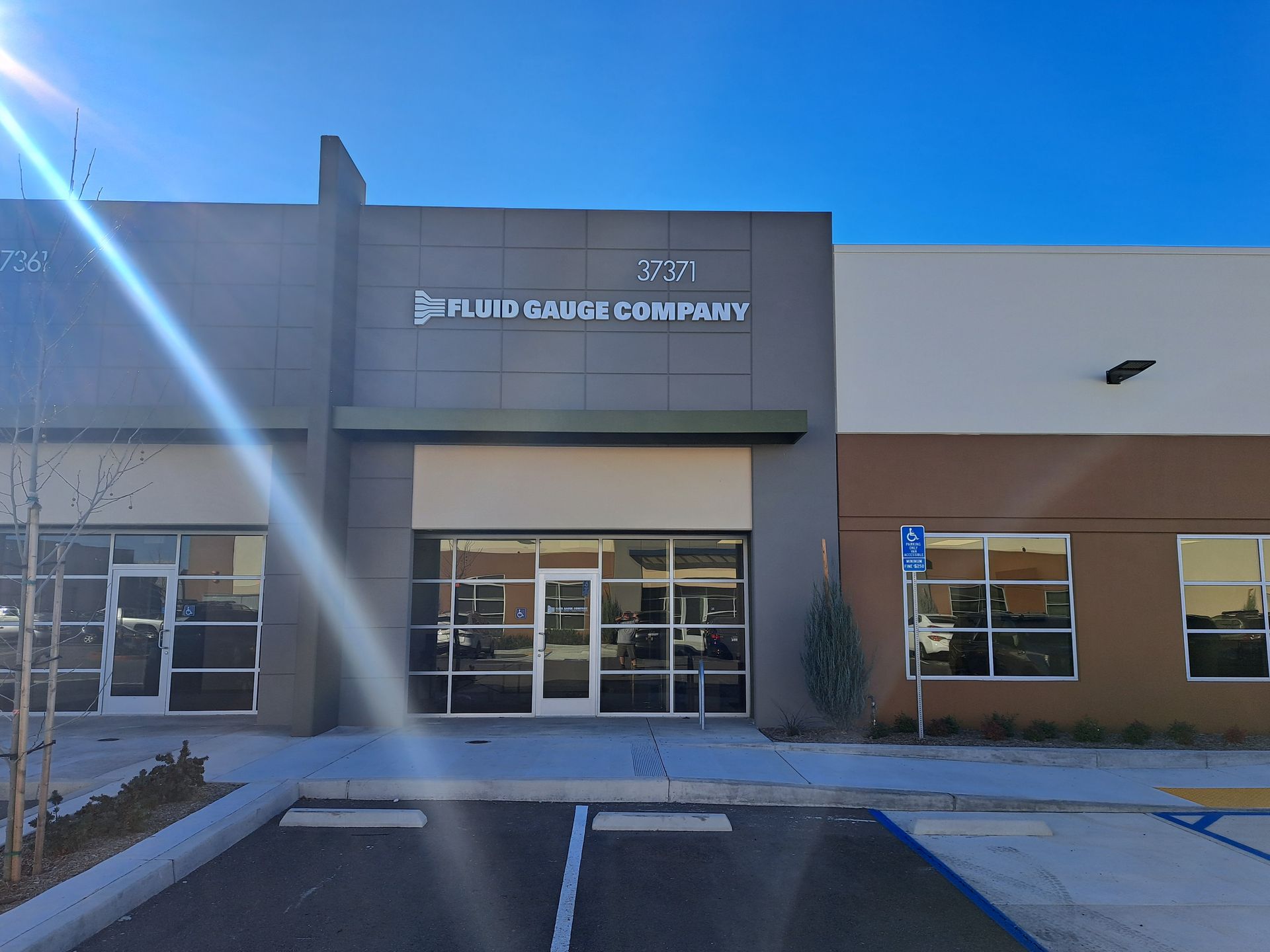 Exterior of a modern office building with a centered entrance and large windows under a blue sky