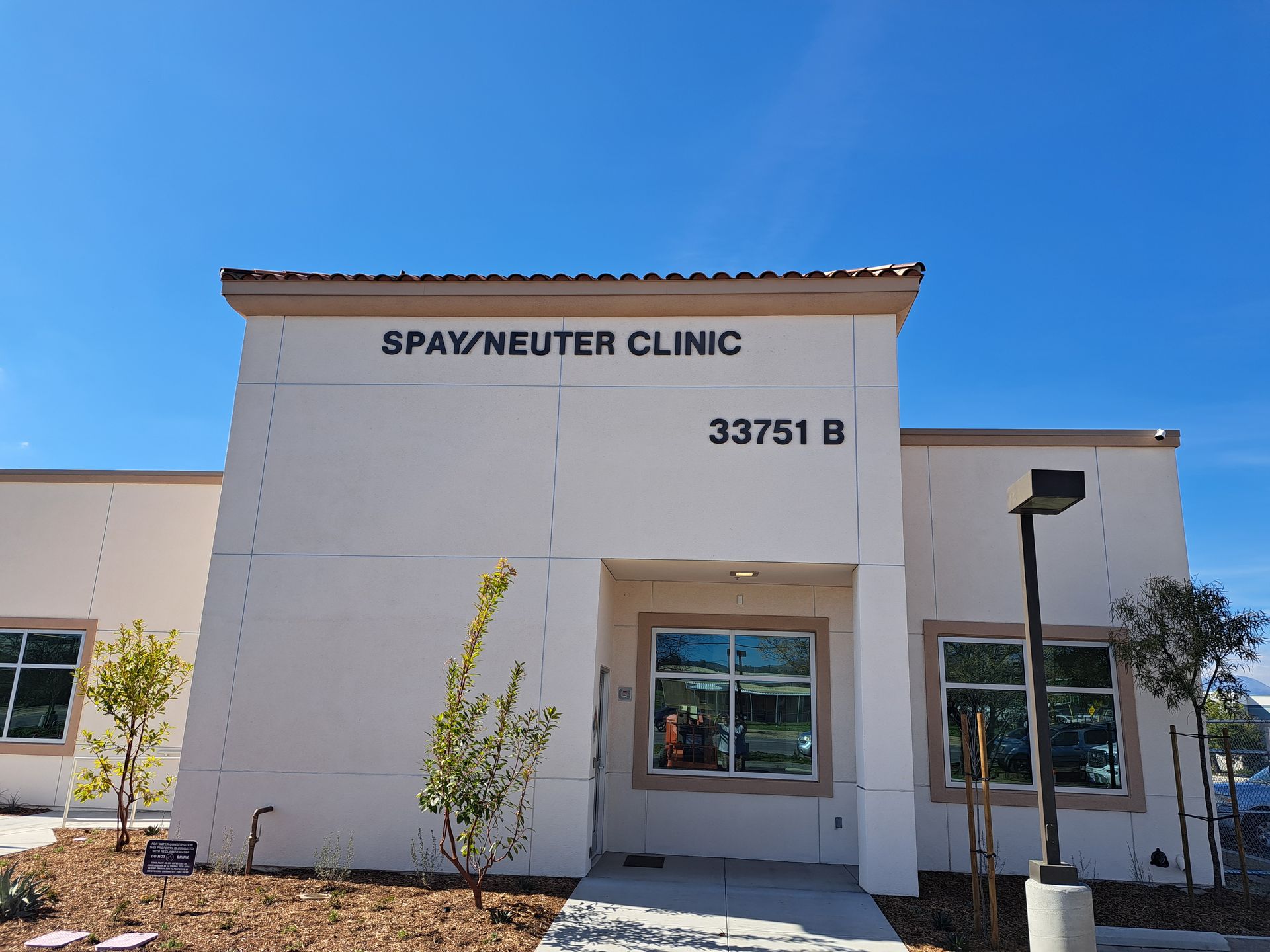 SpaYNeuter Clinic storefront under a blue sky, with white stucco walls and address 33751 B above the entrance.