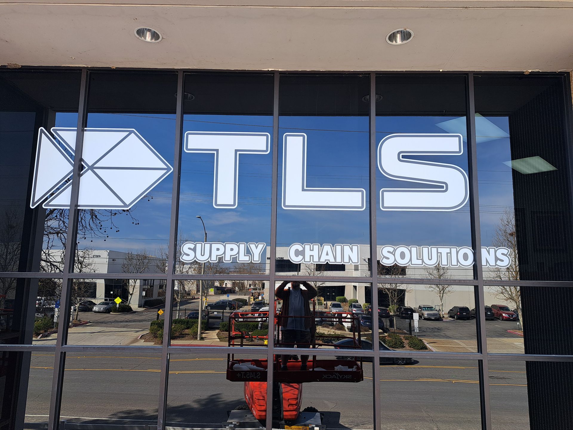 TLS Supply Chain Solutions storefront window with blue logo and reflections outside