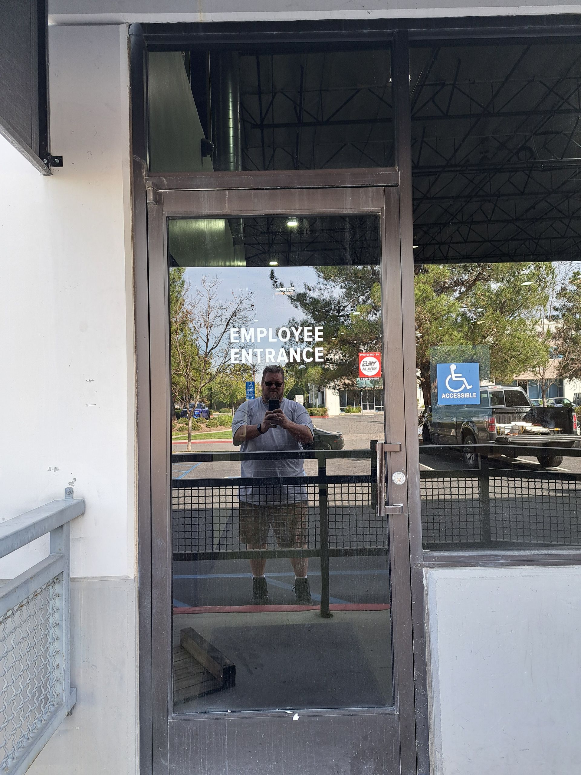 Glass office door labeled “Employee Entrance” with a person reflected inside.