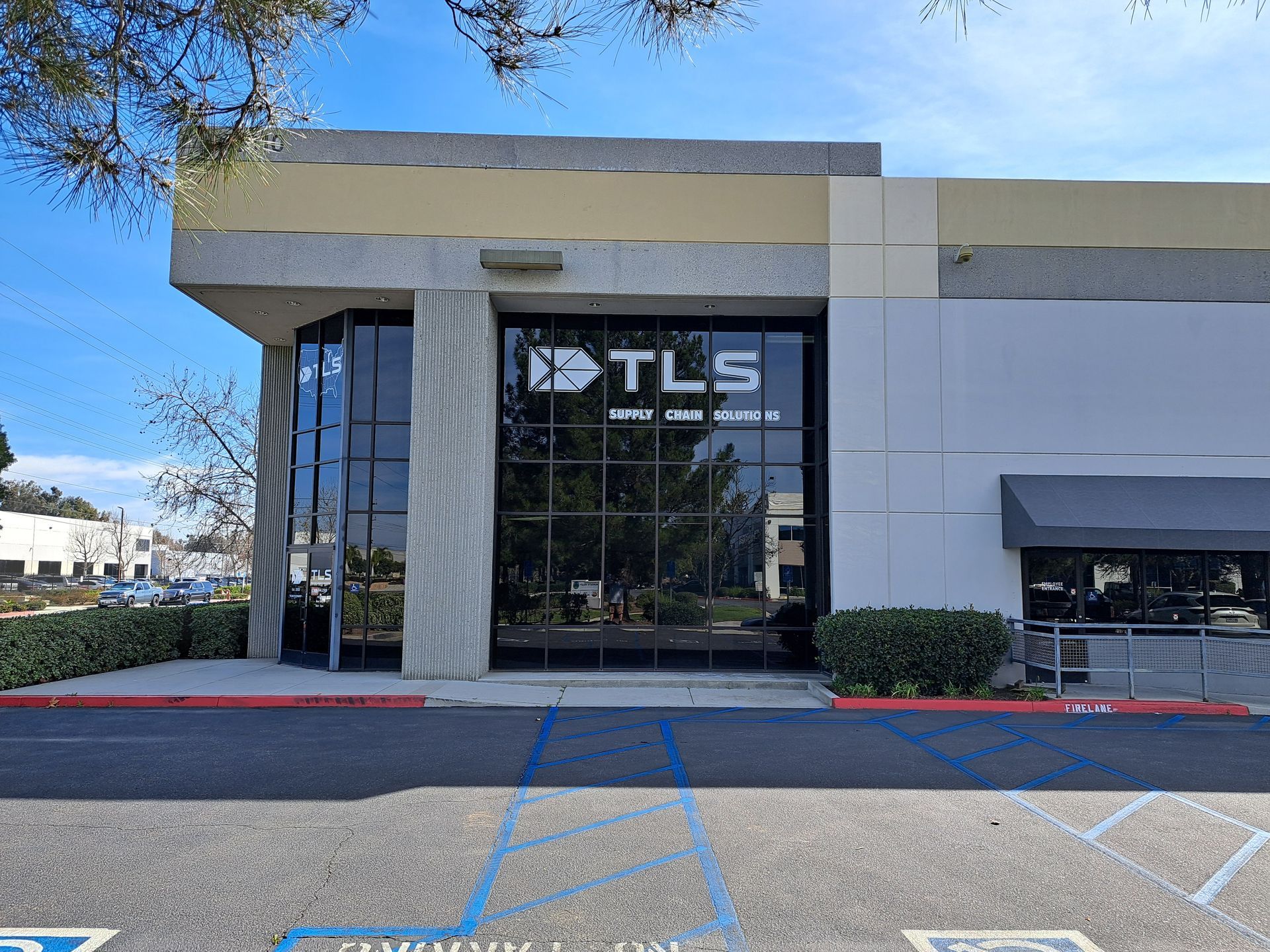 TLS storefront with glass entrance, beige facade, and parking spaces in front