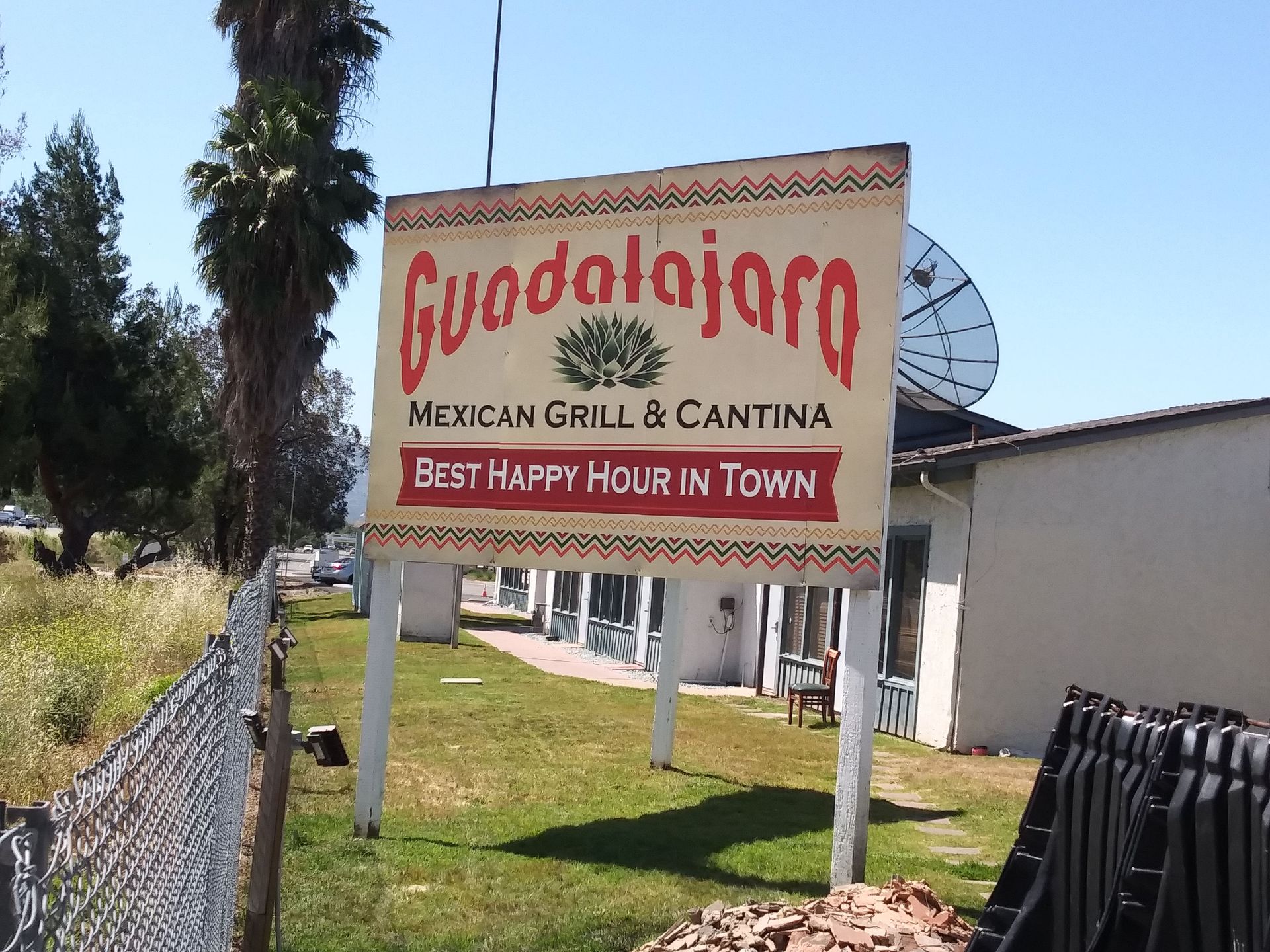 Cudalajojo Mexican Grill & Cantina roadside sign with red lettering and patio umbrella in front of a building