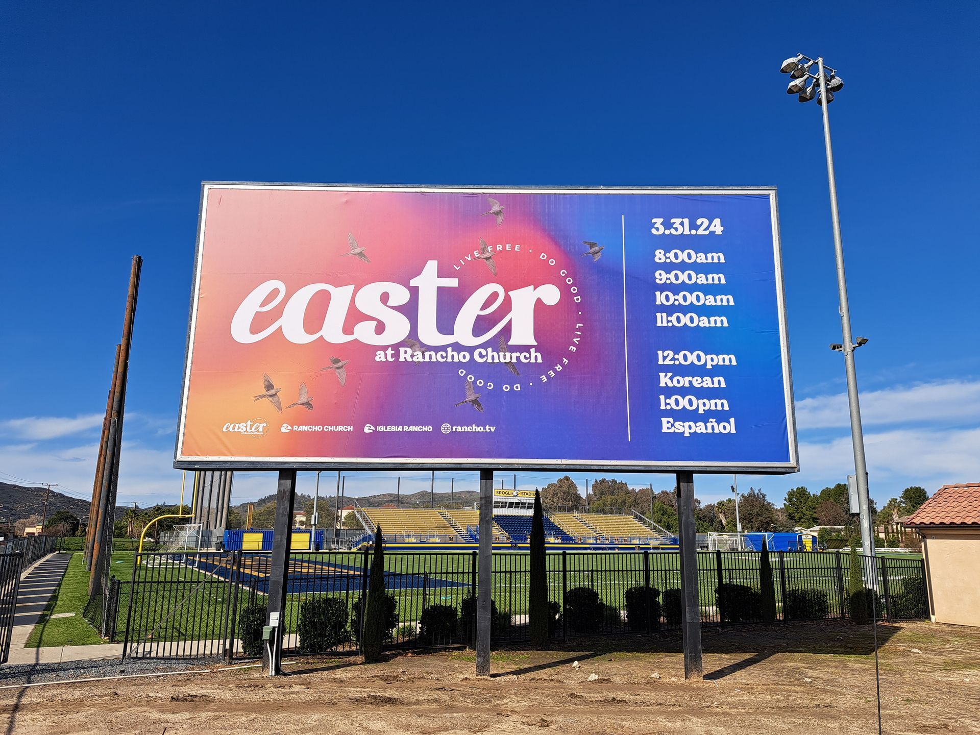 Billboard with “easter” on a pink-purple sky background, beside a road under a clear blue sky.