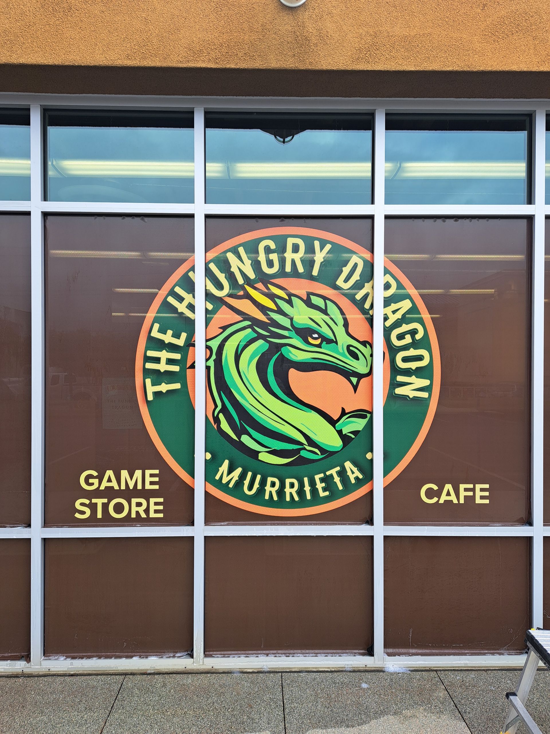 The Angry Dragon game store and cafe sign on a building window in Murrieta.