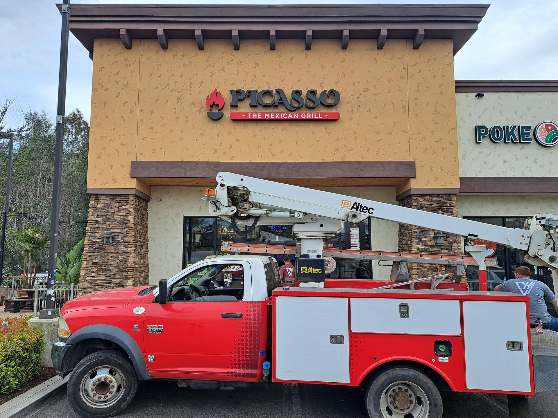 Red utility truck with raised boom parked outside a PHASSO storefront