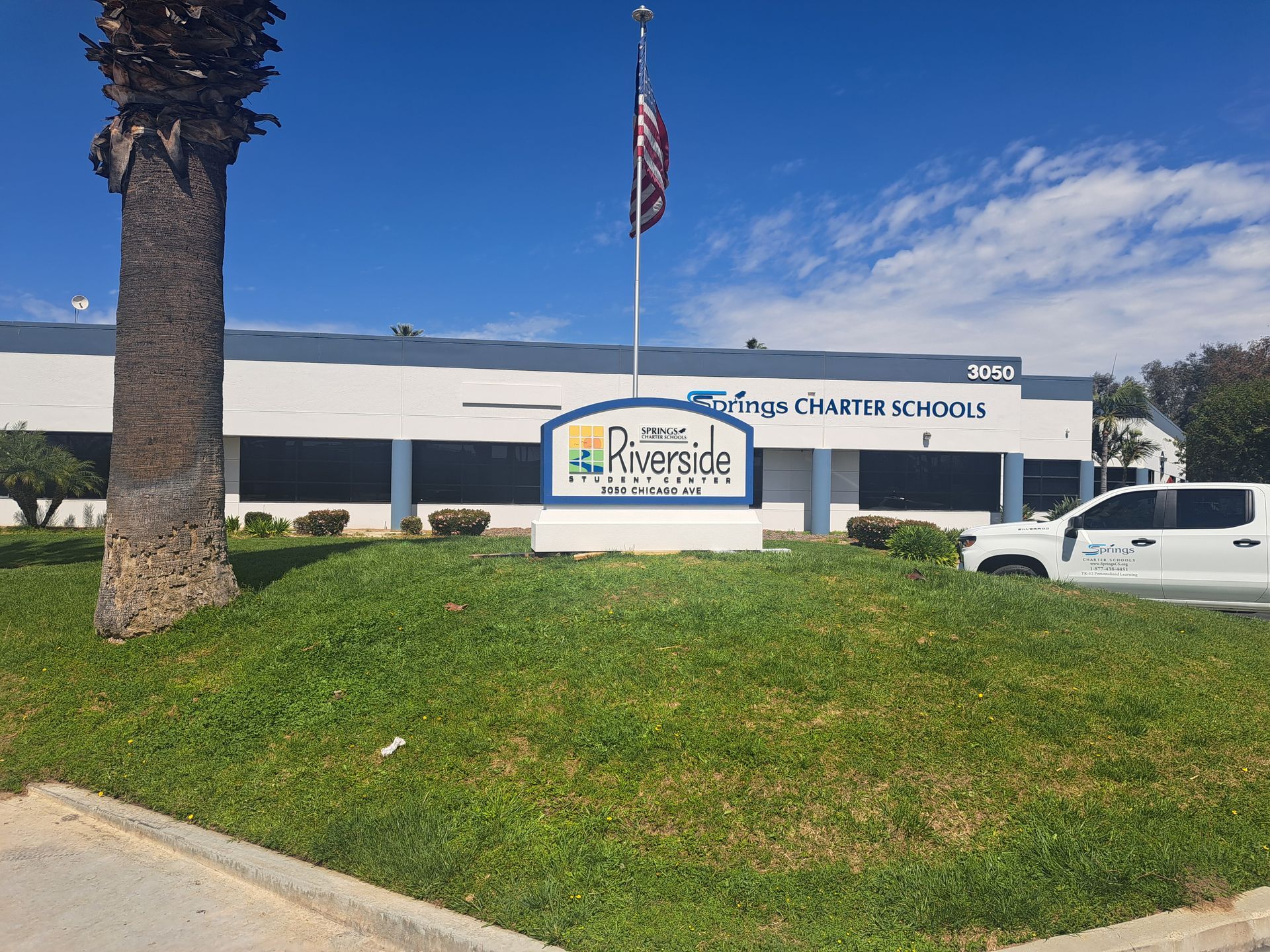 Chester Children’s sign outside a low white building with palm tree, flagpole, grass, and parked white SUV.