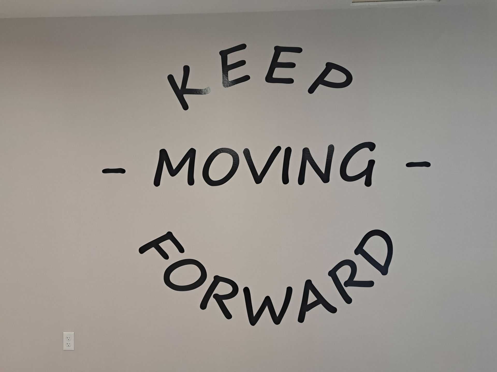 Black wall text reads “KEEP MOVING FORWARD” in a curved layout.