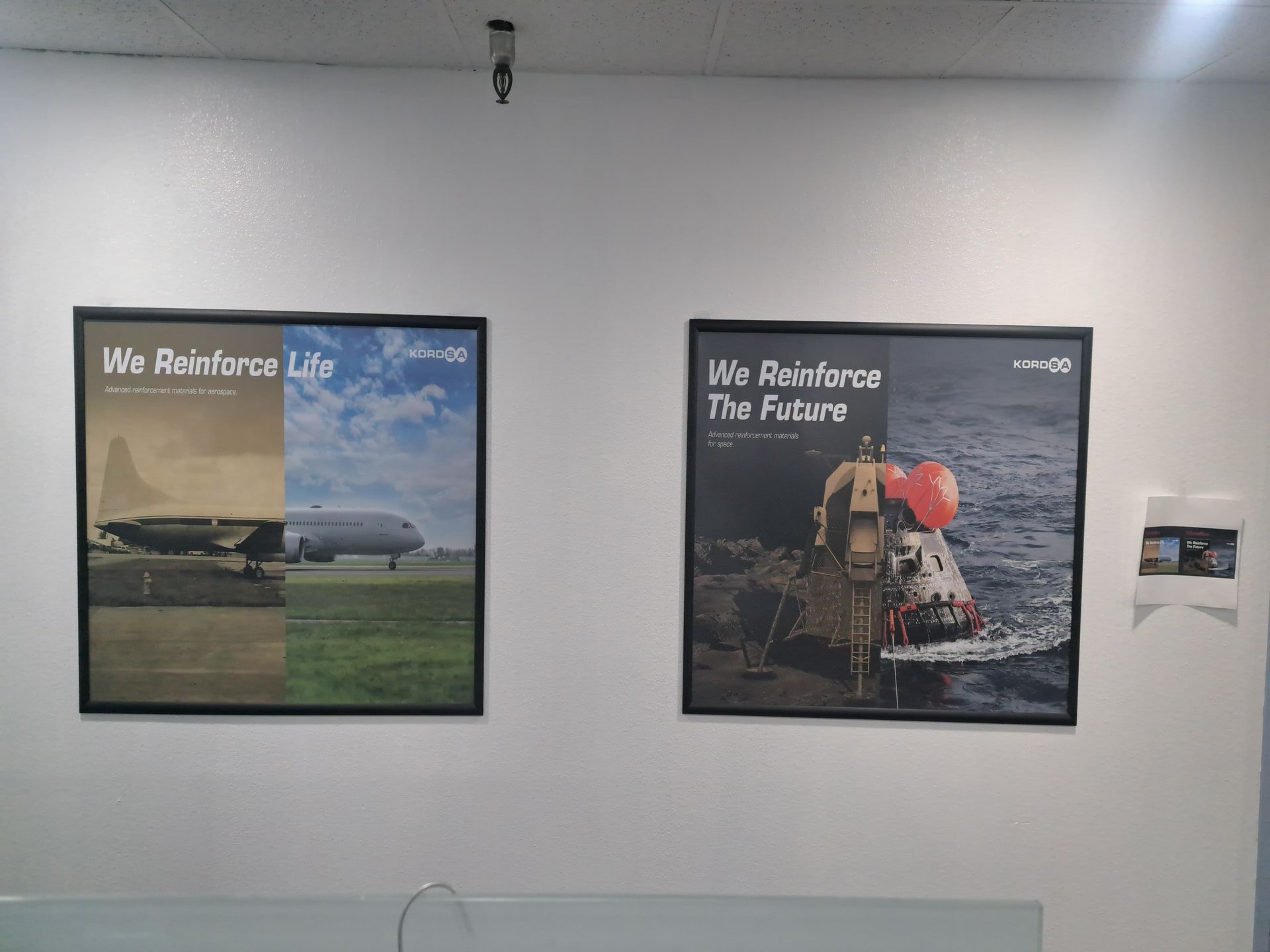 Two framed posters on a white wall, one showing a plane, the other a soldier in snowy terrain.