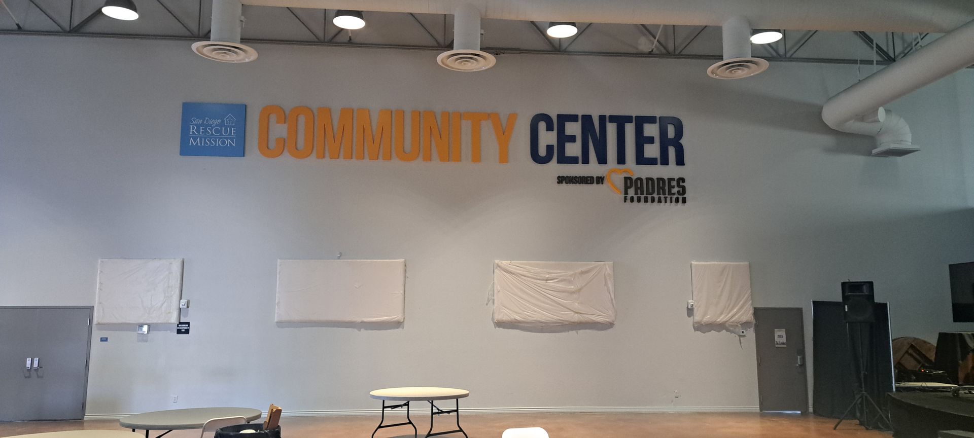 Community center lobby with gray walls, large “COMMUNITY CENTER” sign, and benches along the wall