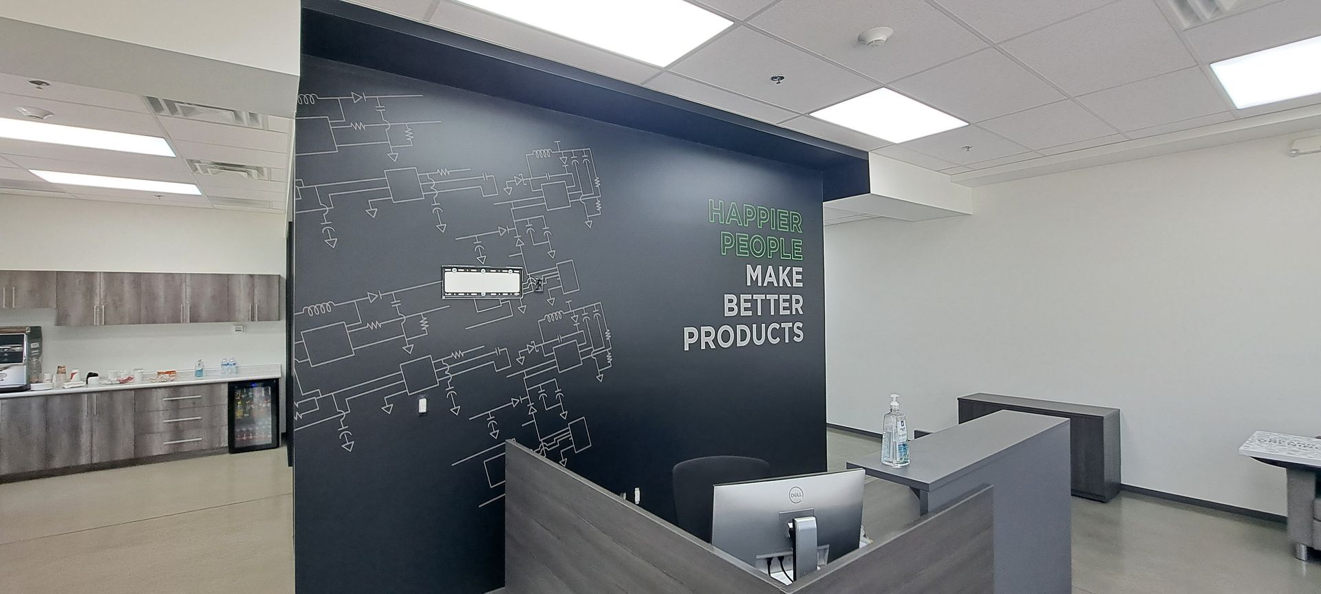 Modern office lobby with dark accent wall, reception desk, and lounge seating under bright ceiling lights