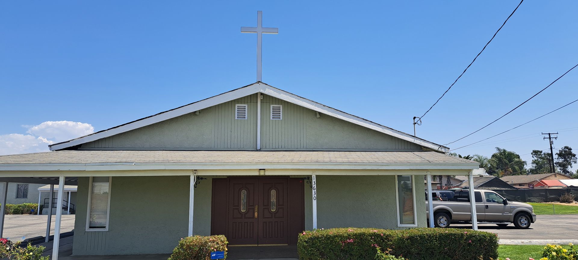 Small church building with a cross on the roof under a clear blue sky