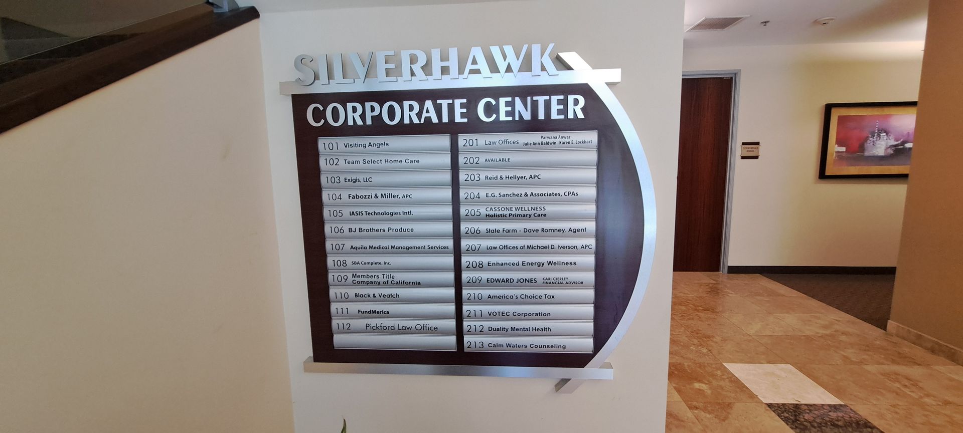 Hallway sign for Silverhawk Corporate Center with tenant directory and lobby corridor in background