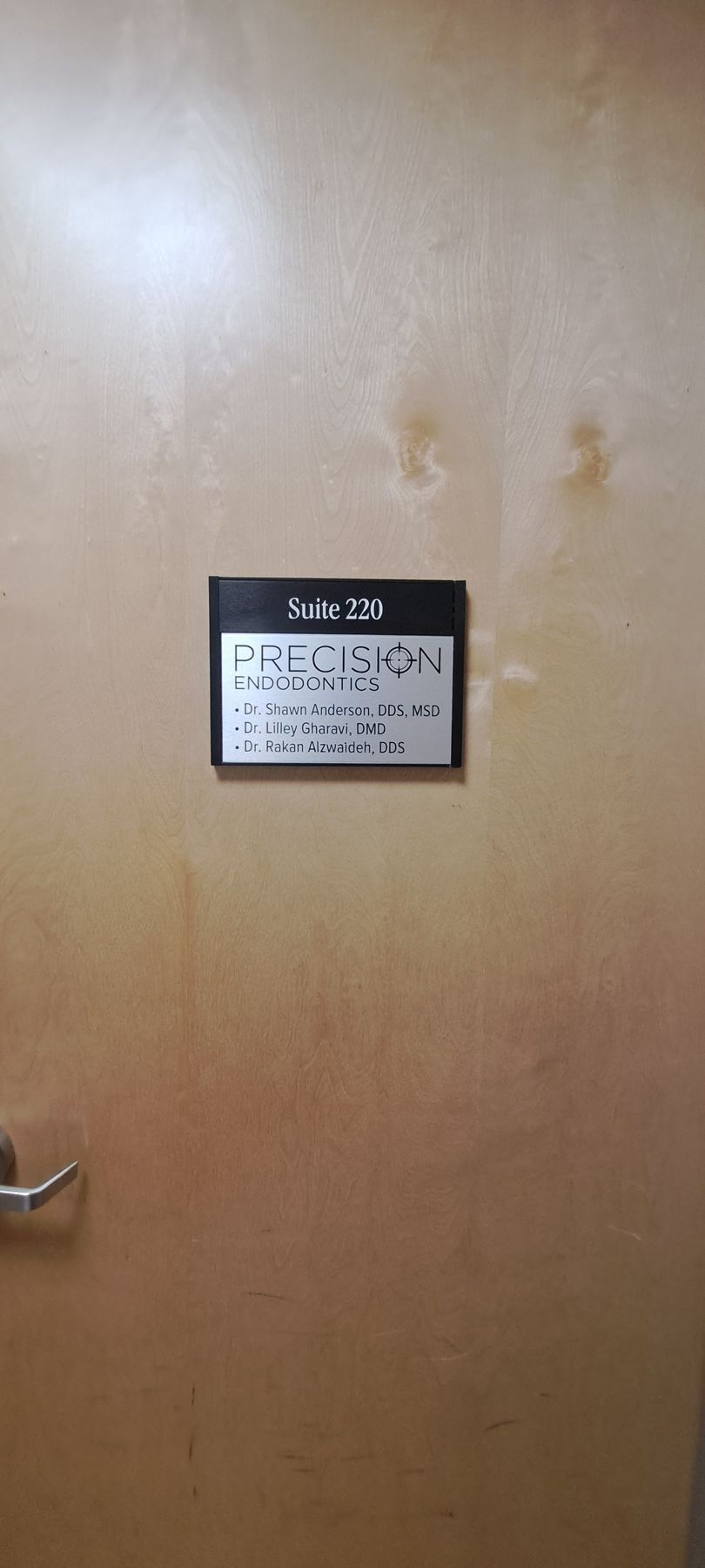 Wooden door with a small sign and a metal handle on the left side.
