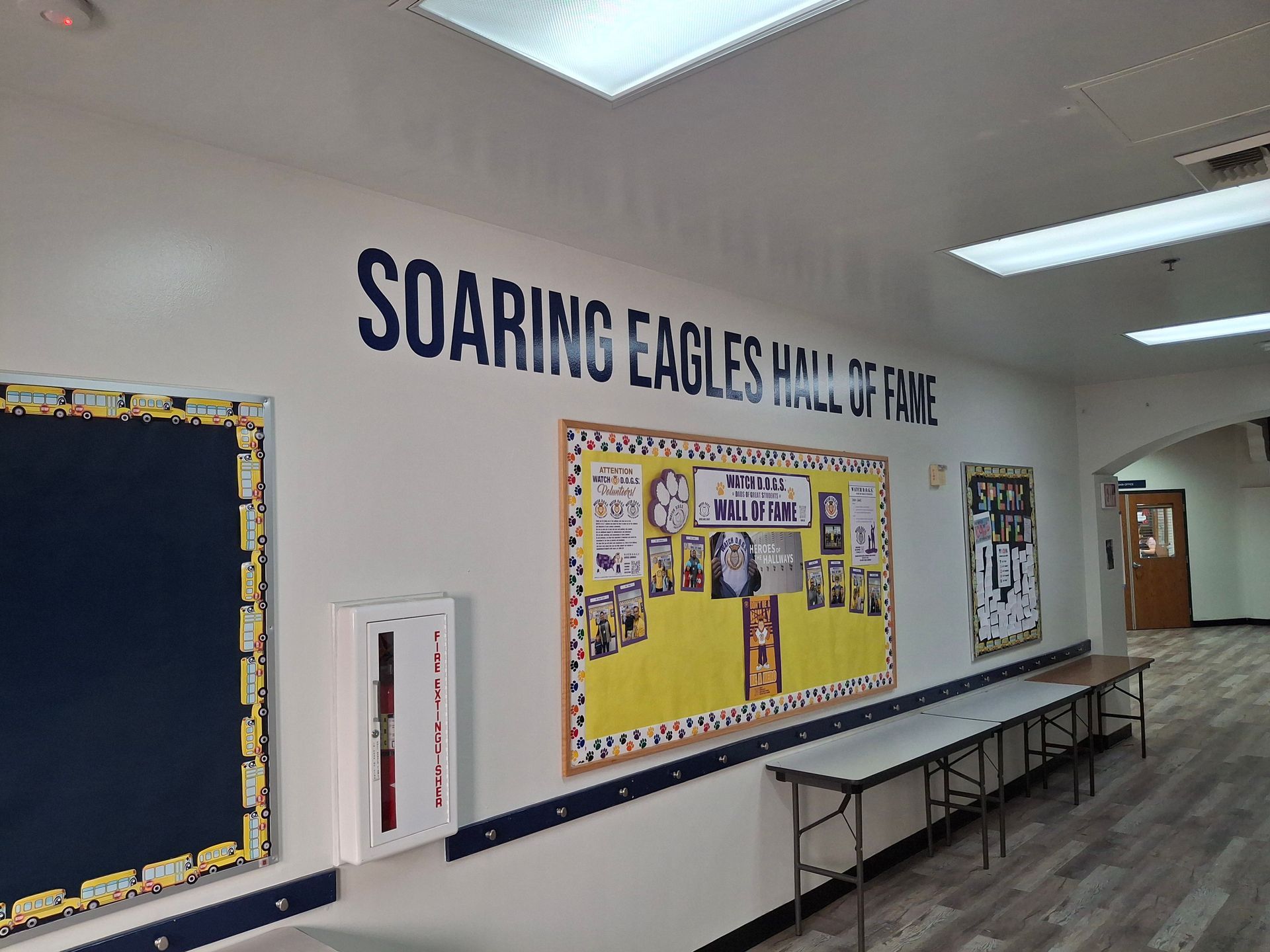 School hallway with bulletin boards and a long bench under the “Soaring Eagles” wall sign.