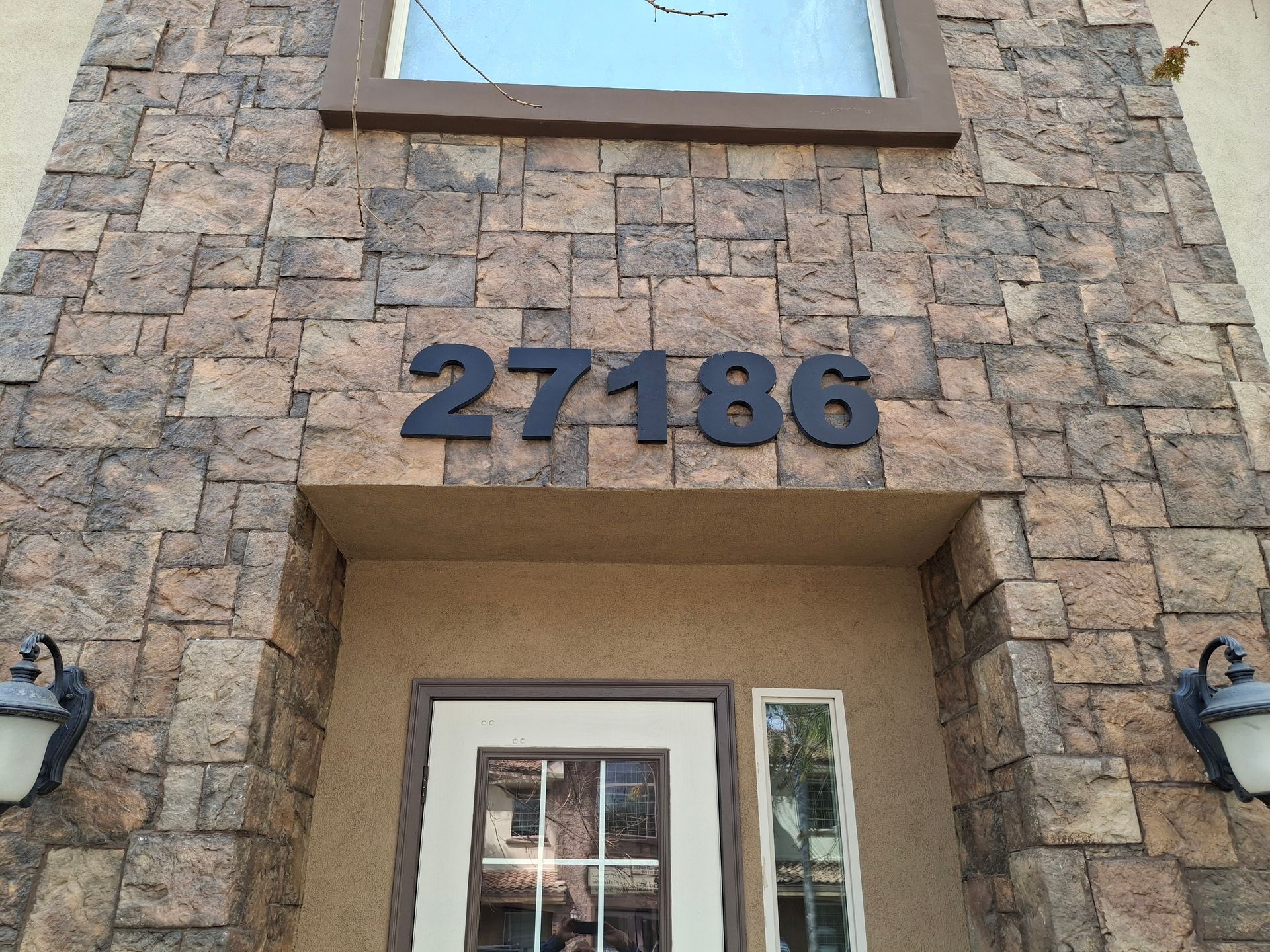 Stone building entrance with house number 27186 above the doorway