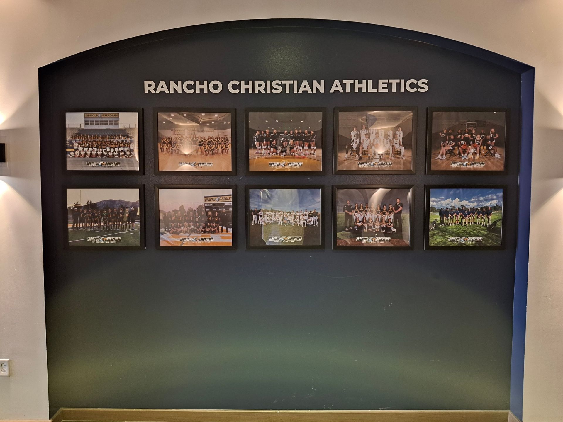Rancho Christian Athletics display board with multiple sports team photos on a dark wall