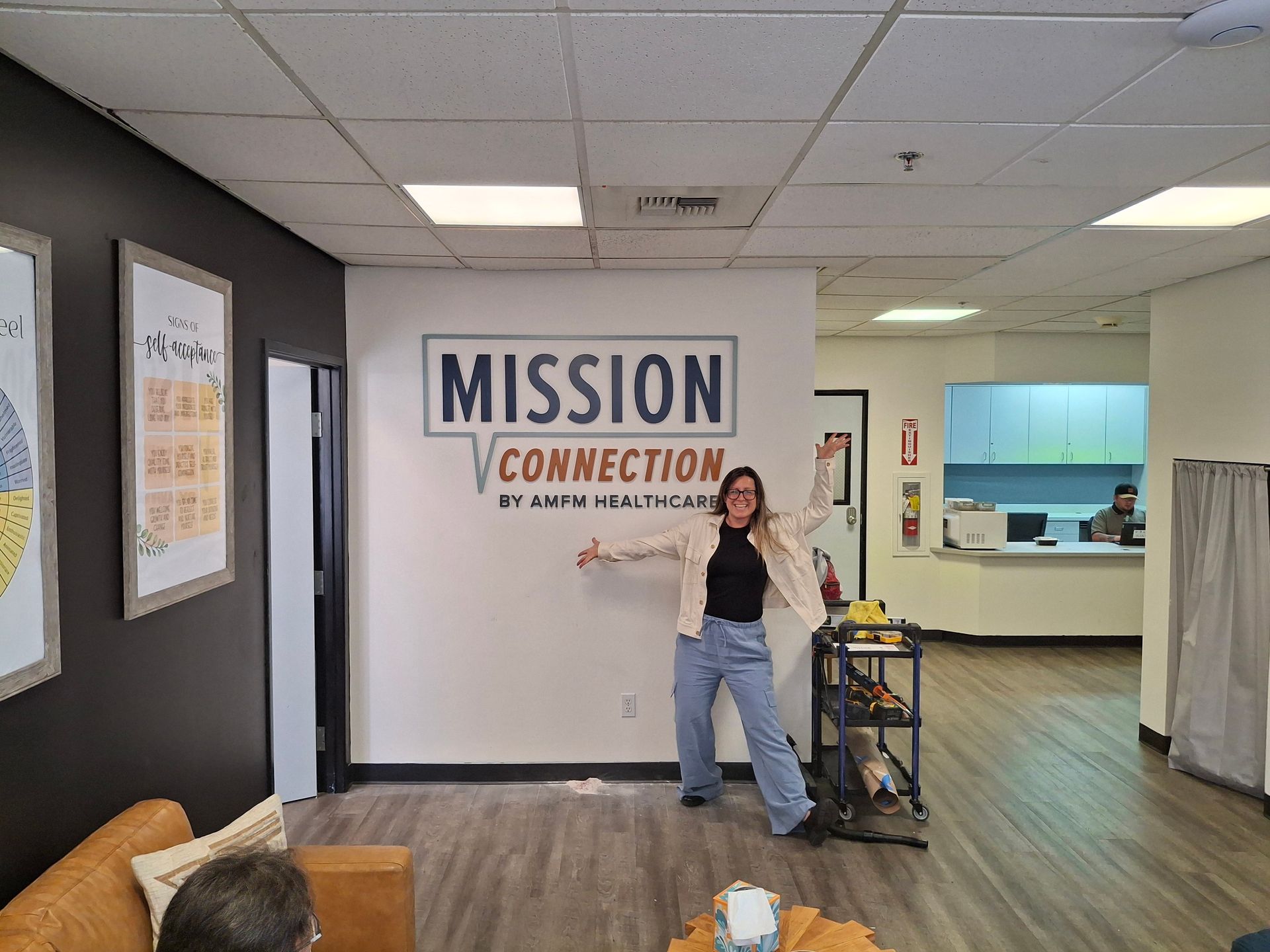 Lobby with “MISSION CONNECTION” sign; person posing by a cart in a bright hallway