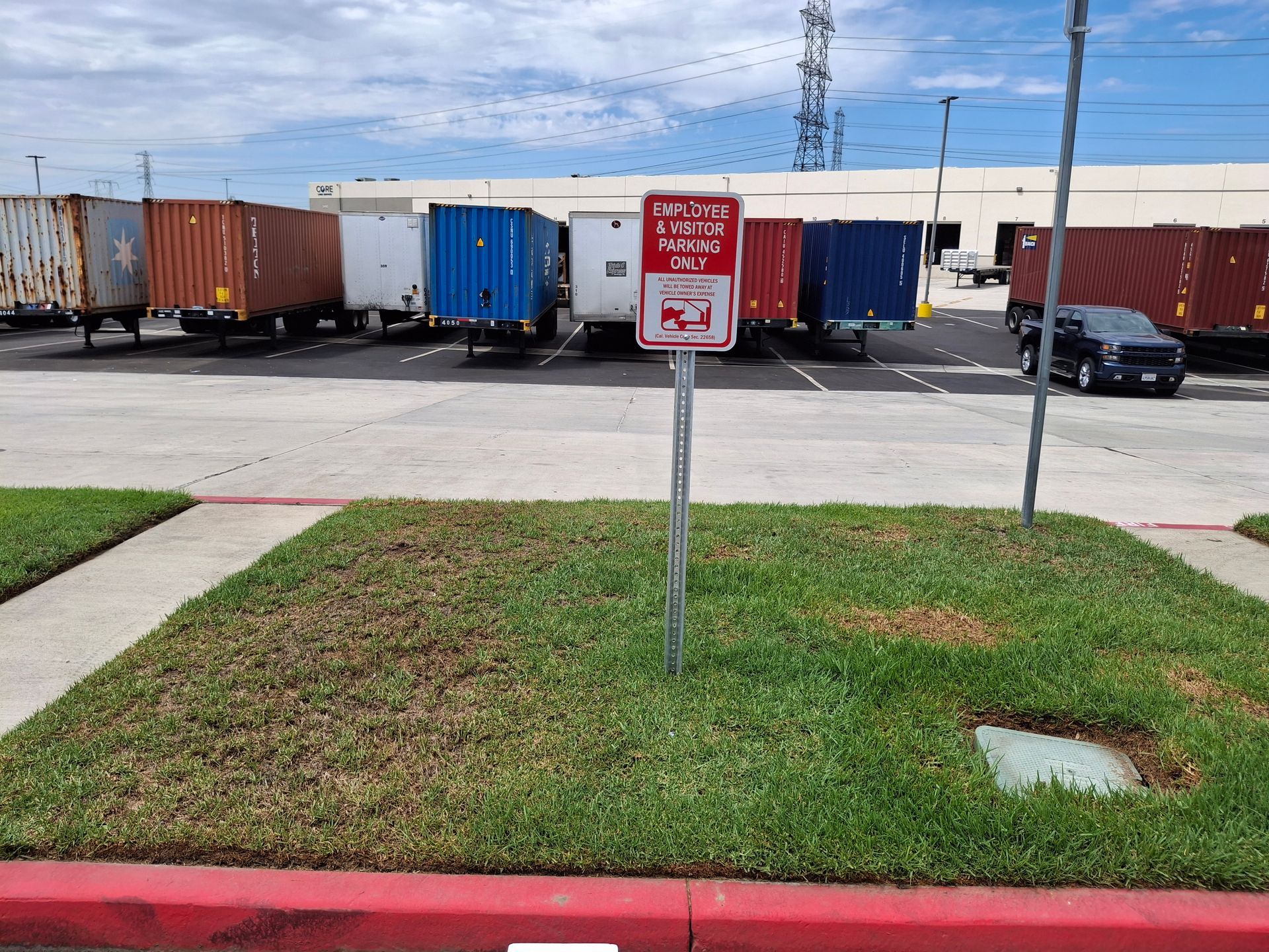 Red no parking sign in front of loading dock with freight trailers and truck bays