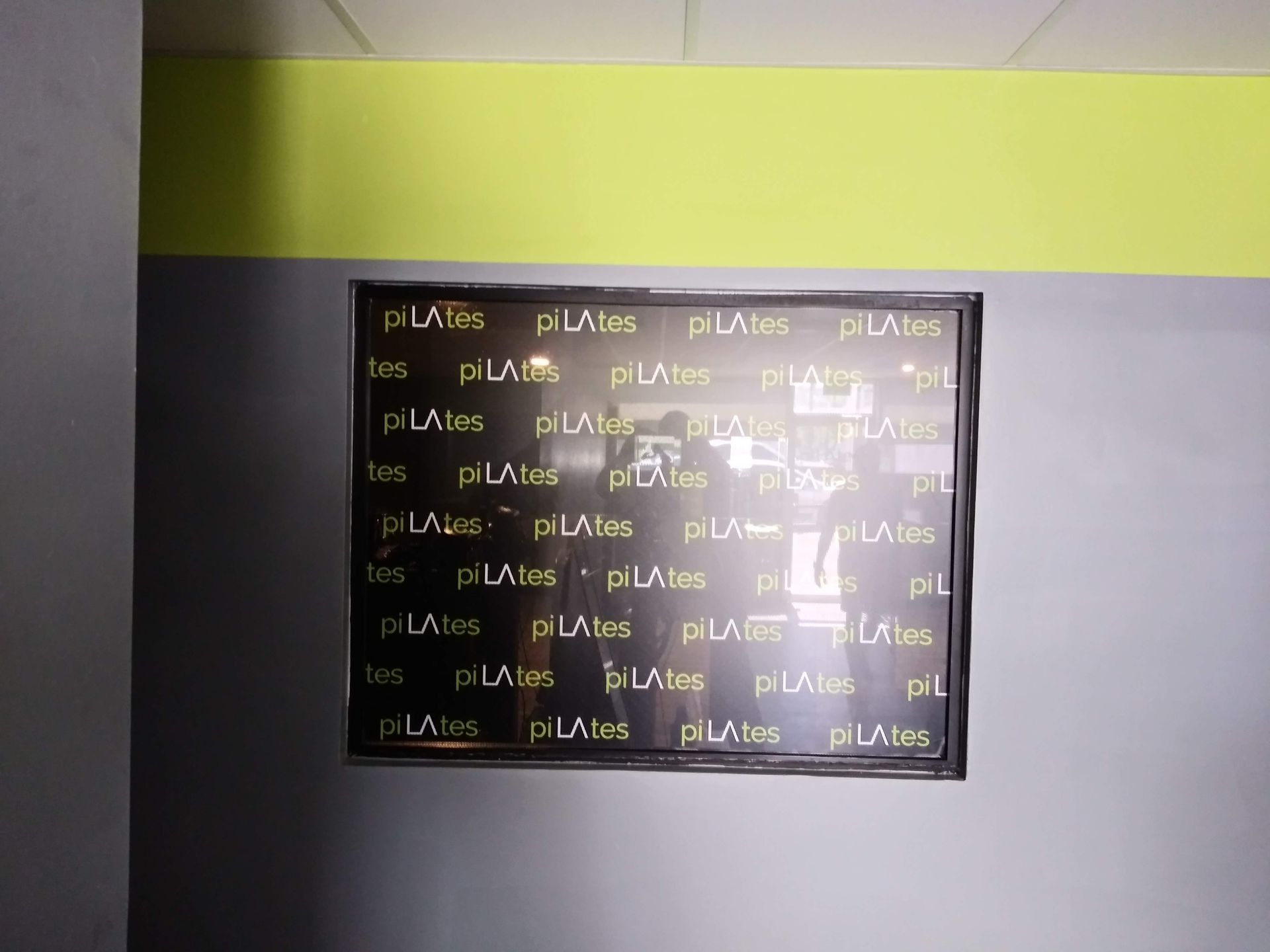 Dark wall with a framed poster covered in repeated text beneath a lime-green ceiling strip