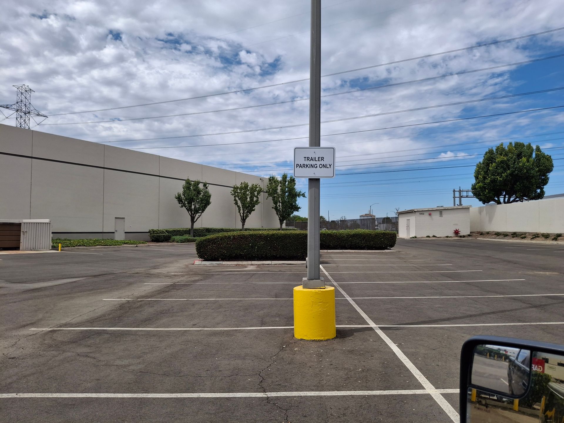 Empty parking lot with a signpost, yellow base, and cloudy sky