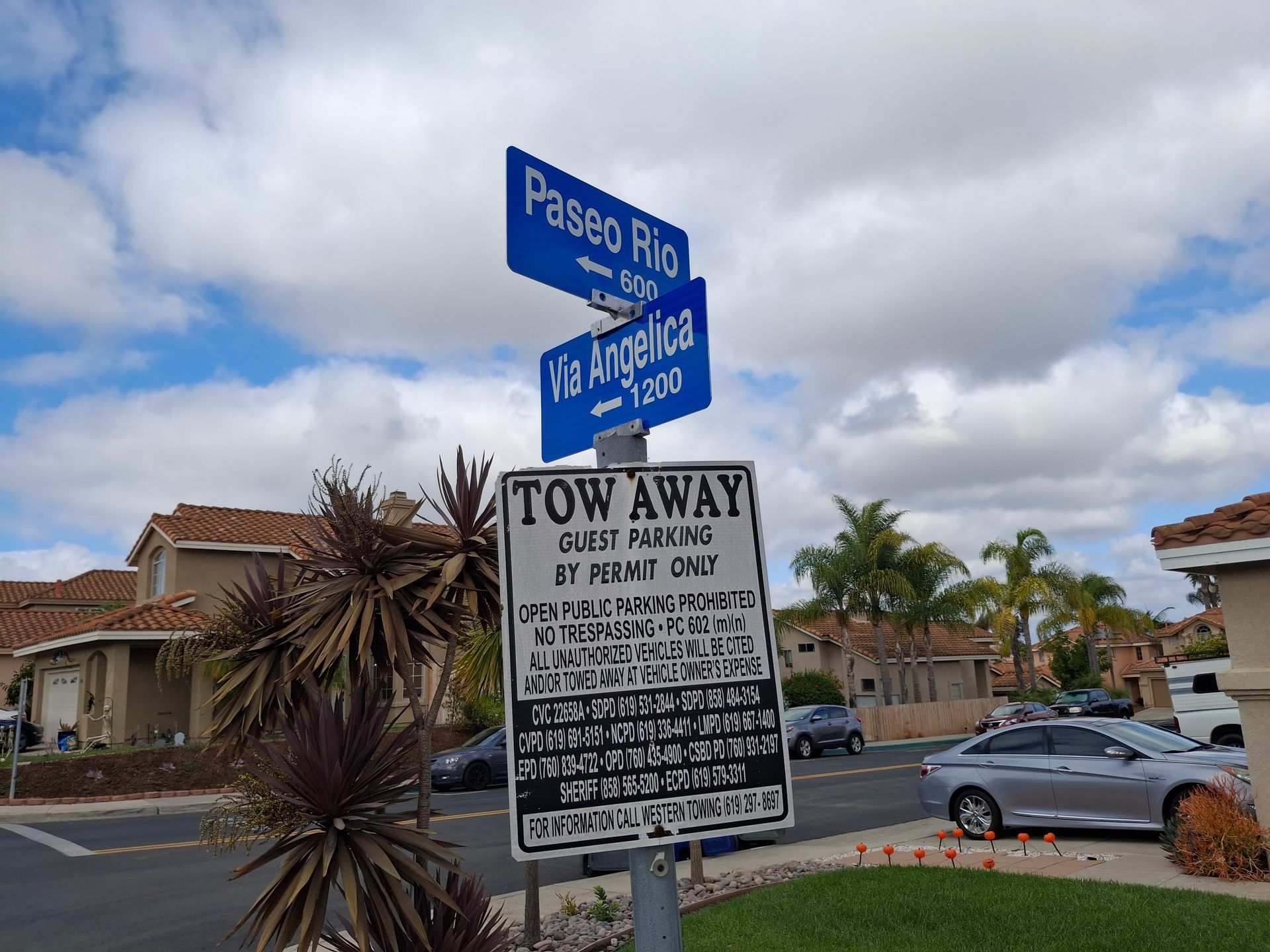 Street signs for Paseo Rio and La Encantada above a towing warning sign in a parking lot.