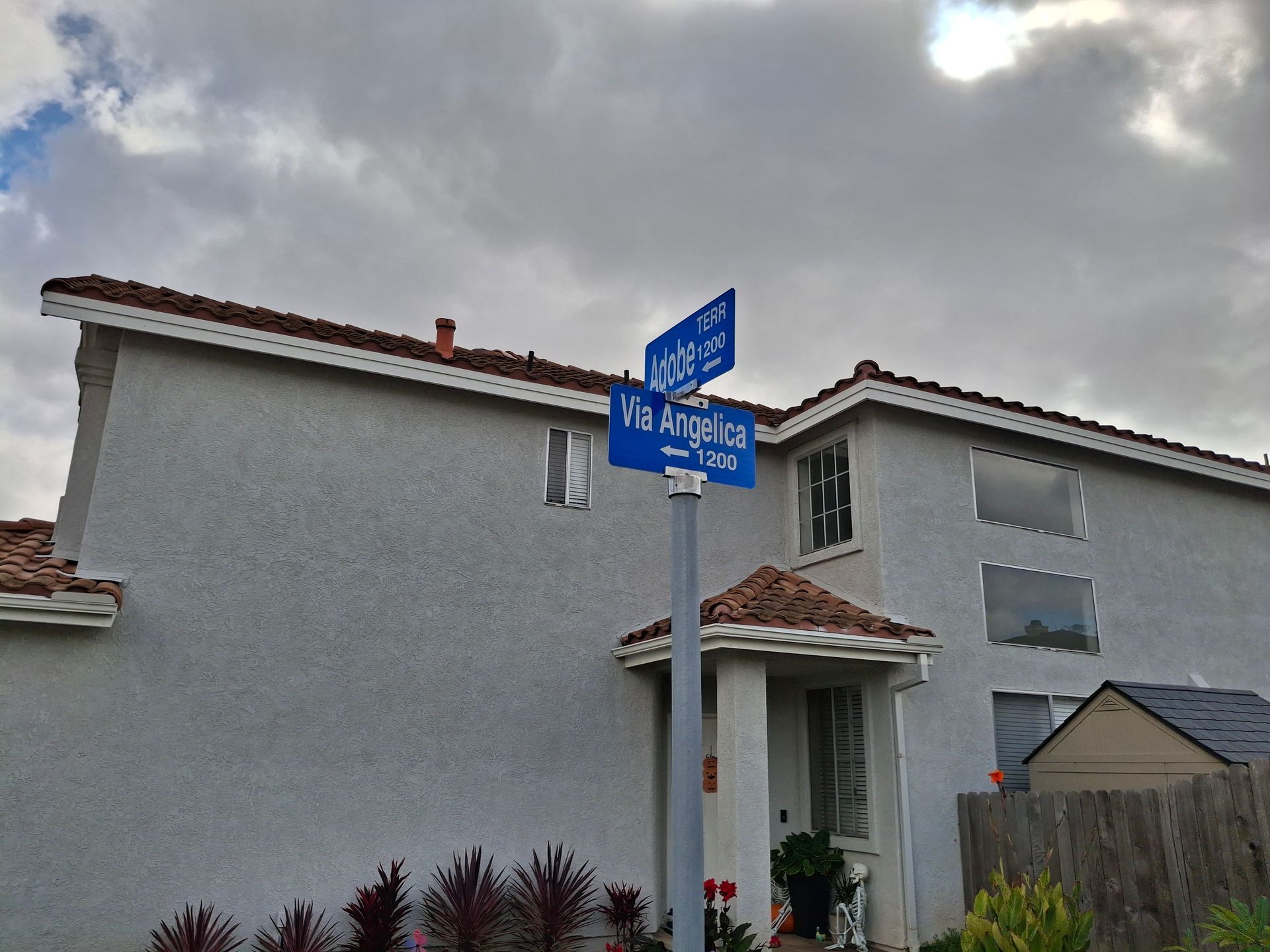 Suburban house with a blue street sign in front under a cloudy sky