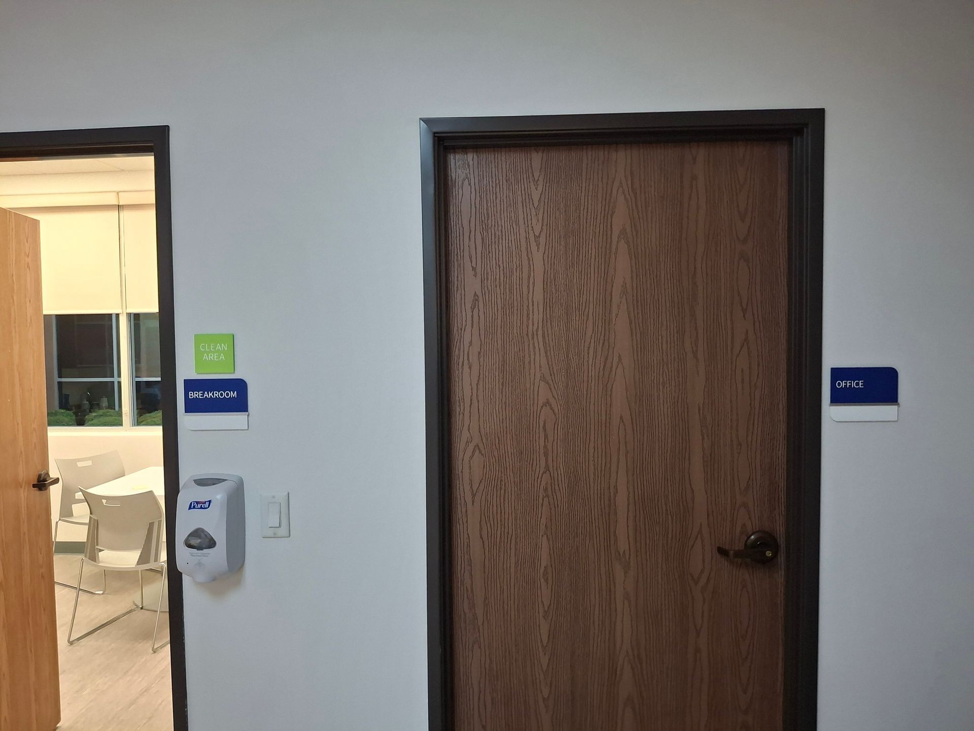 Hallway with two doors: an open room on the left and a closed wooden door on the right.