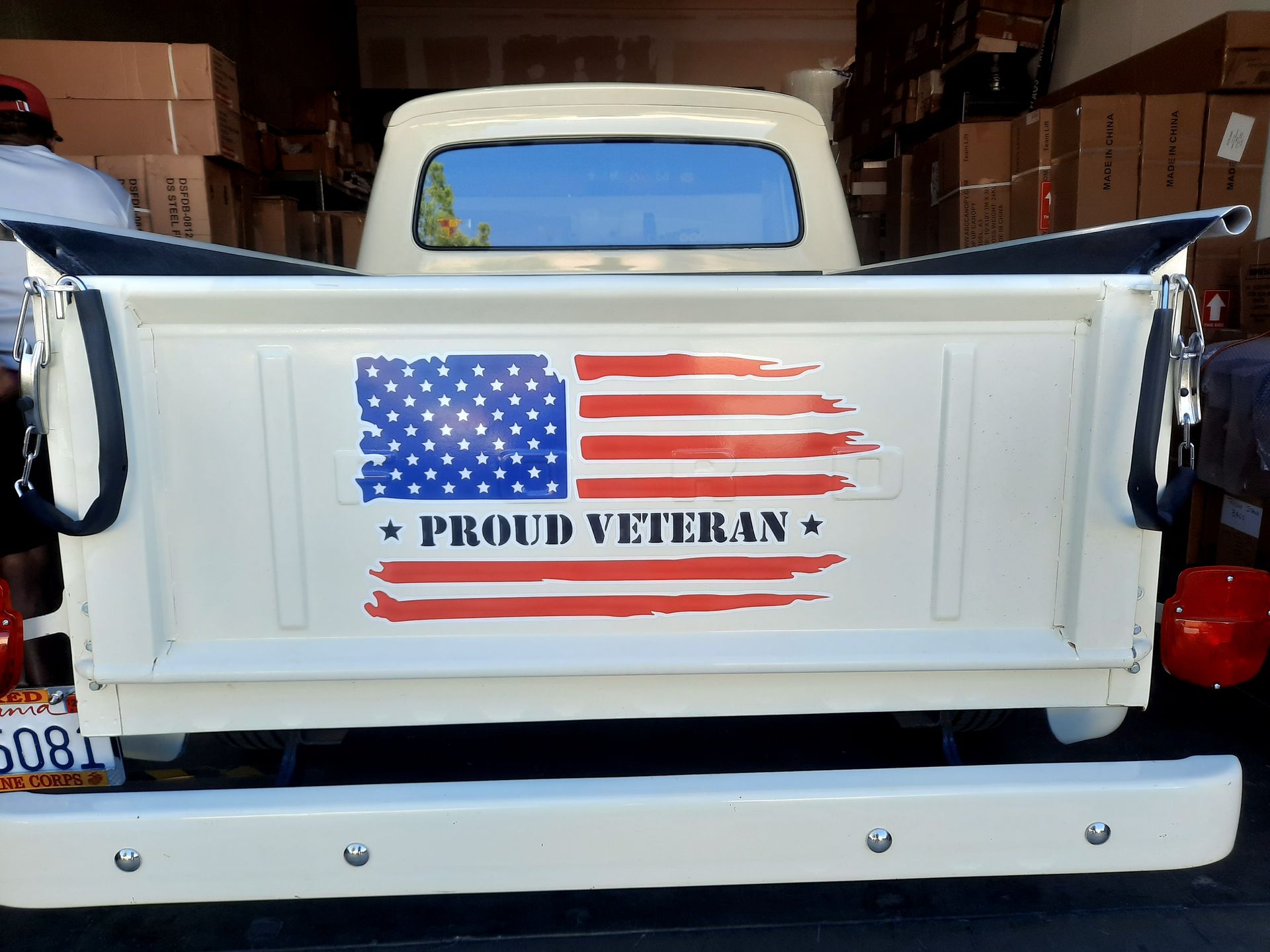 White pickup tailgate with American flag and “Proud Veteran” decal in a garage