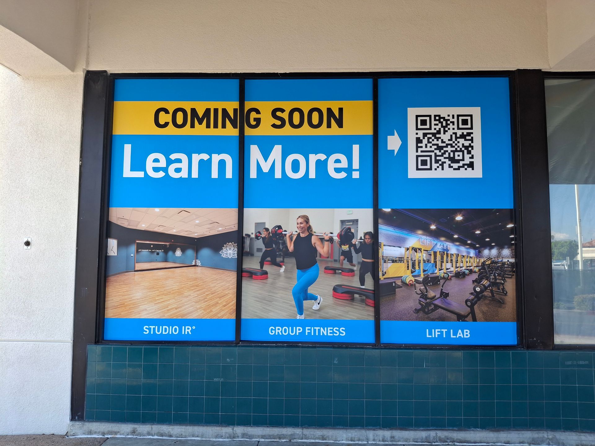 Storefront window sign reading “Coming Soon Learn More!” with photos and a QR code.
