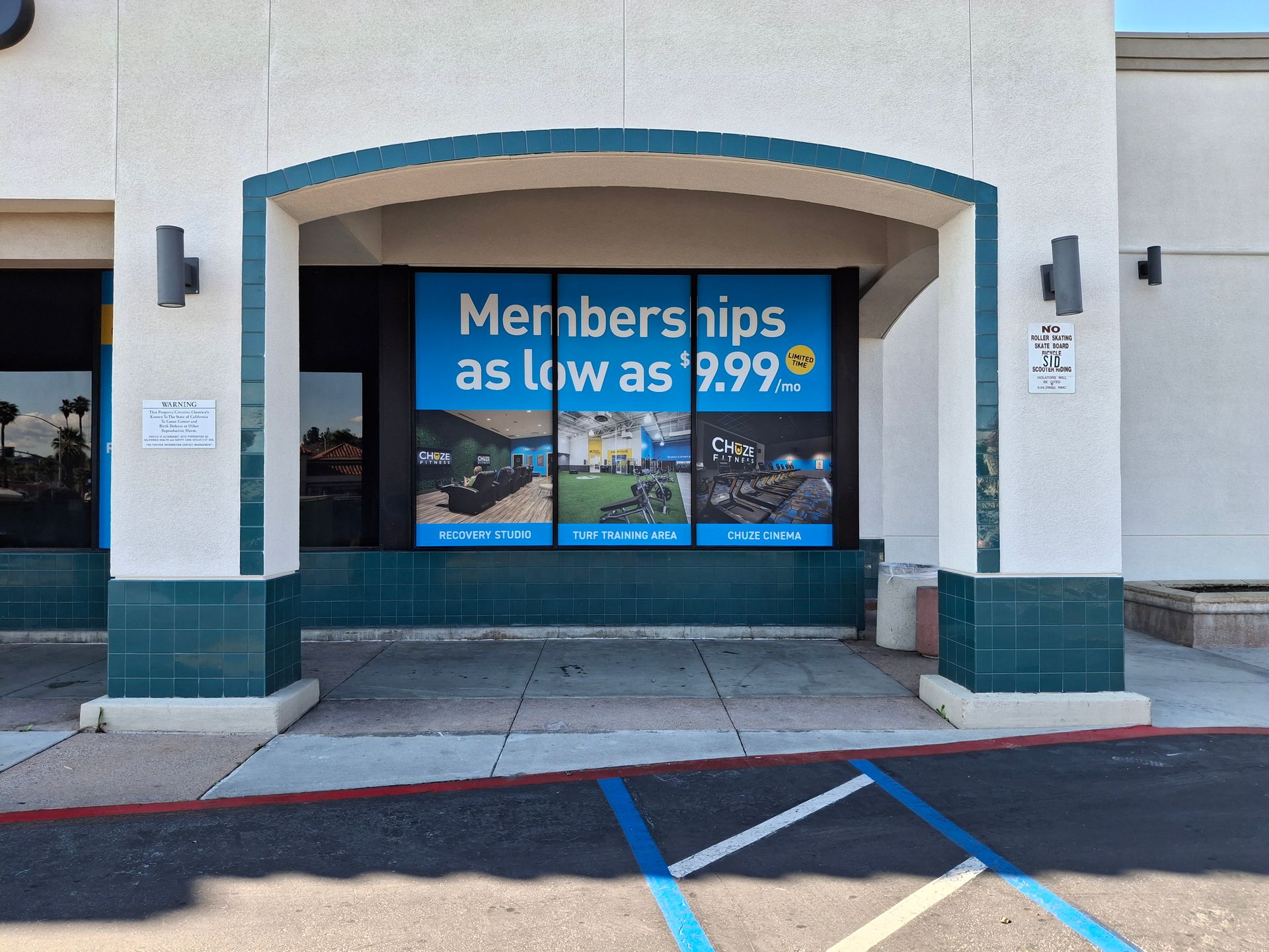 Storefront entrance with blue “Members save as low as $9.99” window sign and accessible parking space