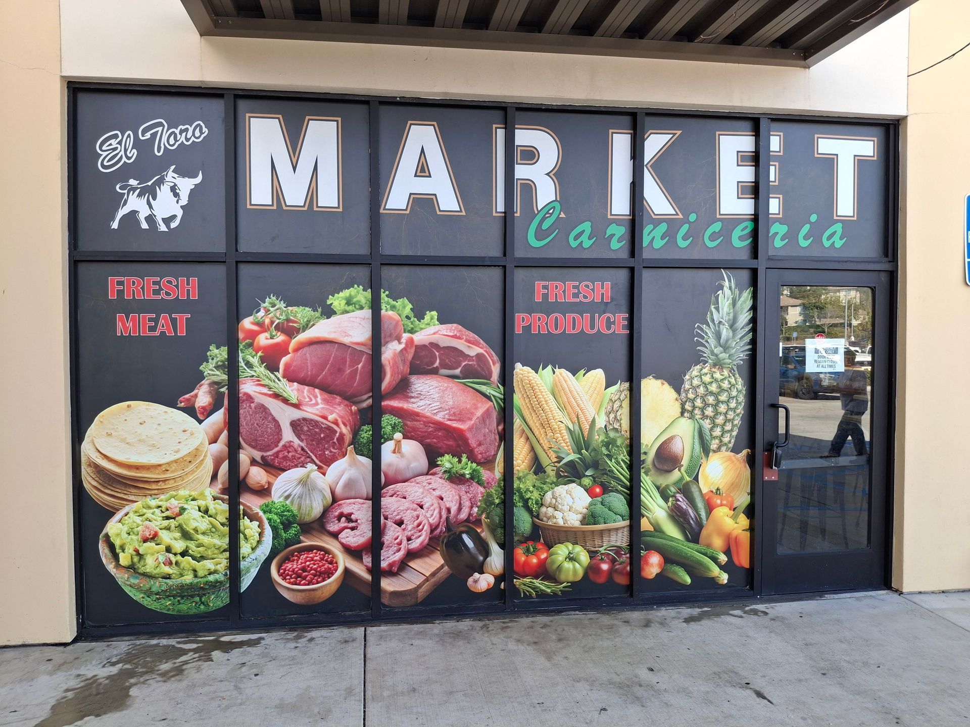 Market storefront with colorful produce and meat graphics, labeled “Market cafeteria” and “Fresh Meat/Produce.”