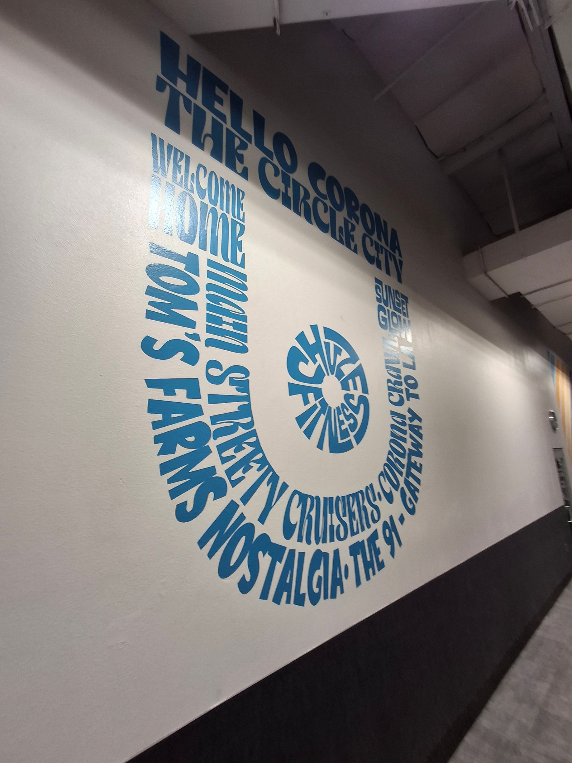 White hallway wall with large blue mural text reading “HELLO, MY NAME IS” and “WE ARE STARS” beside a blue emblem