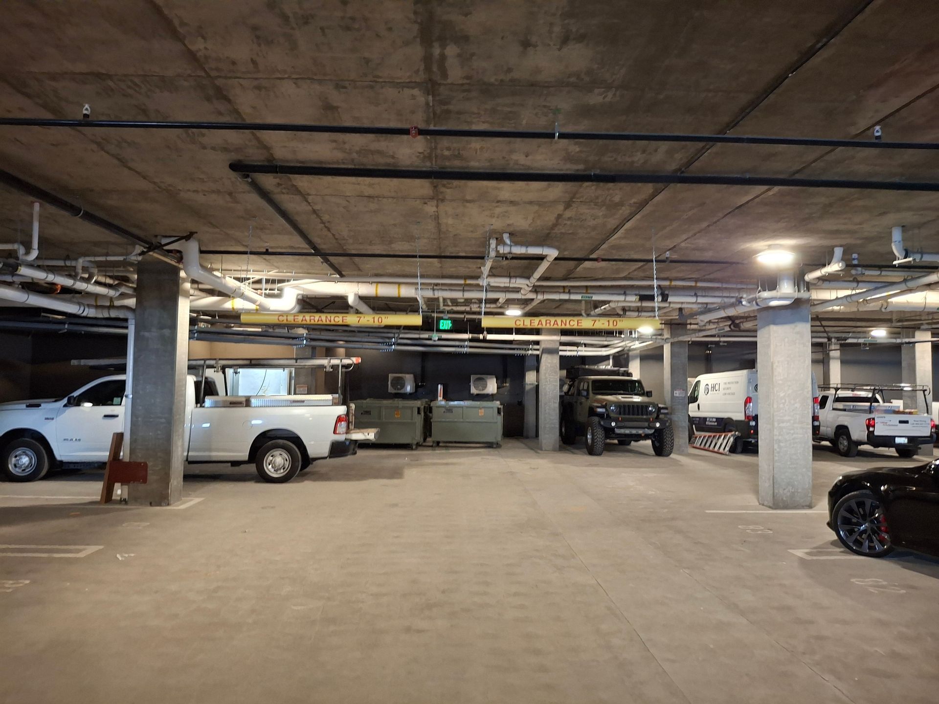 Underground parking garage with several parked cars and exposed concrete ceiling