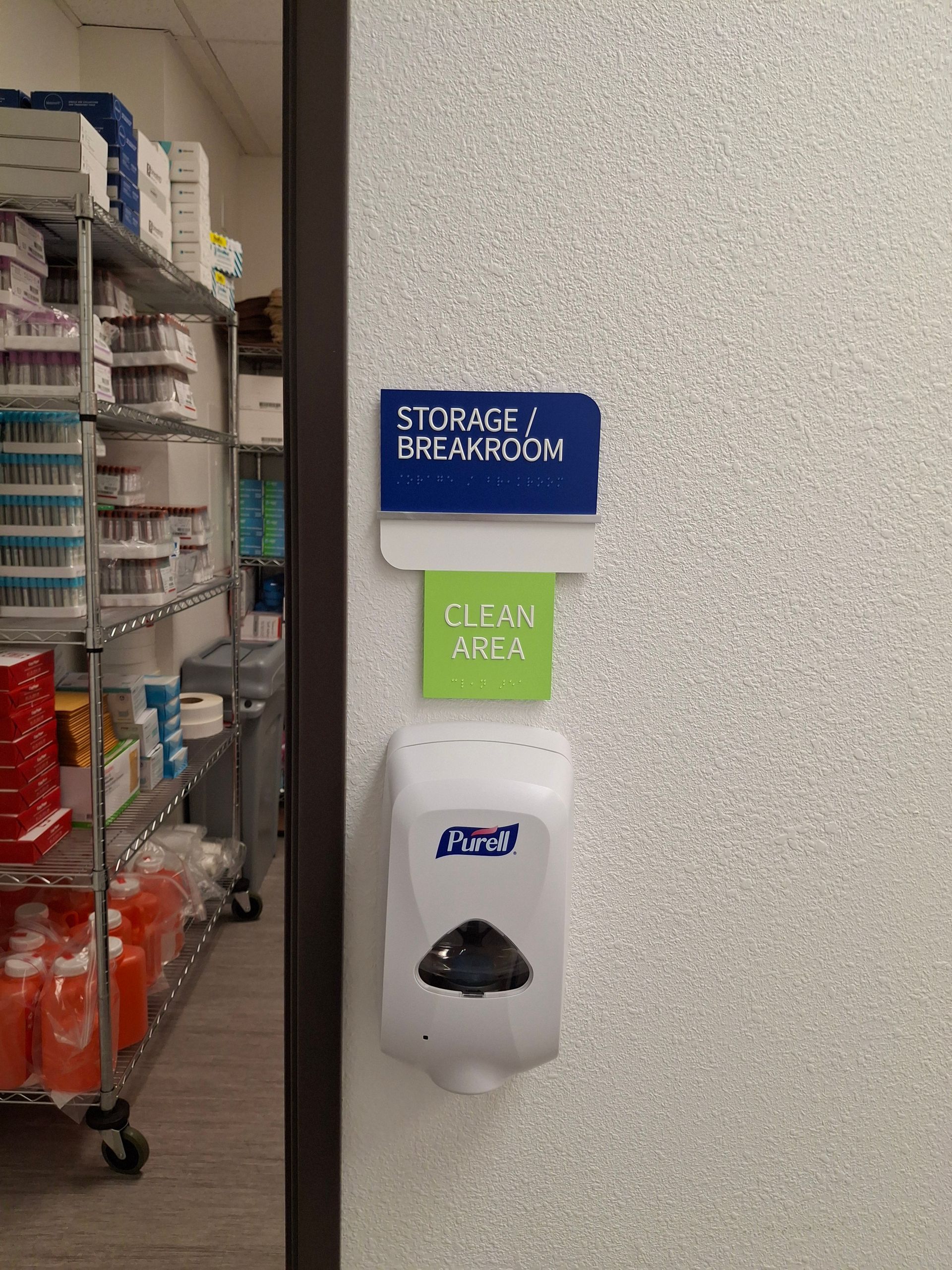 Hallway sign for staircase and bedroom above a wall sanitizer dispenser in a store aisle