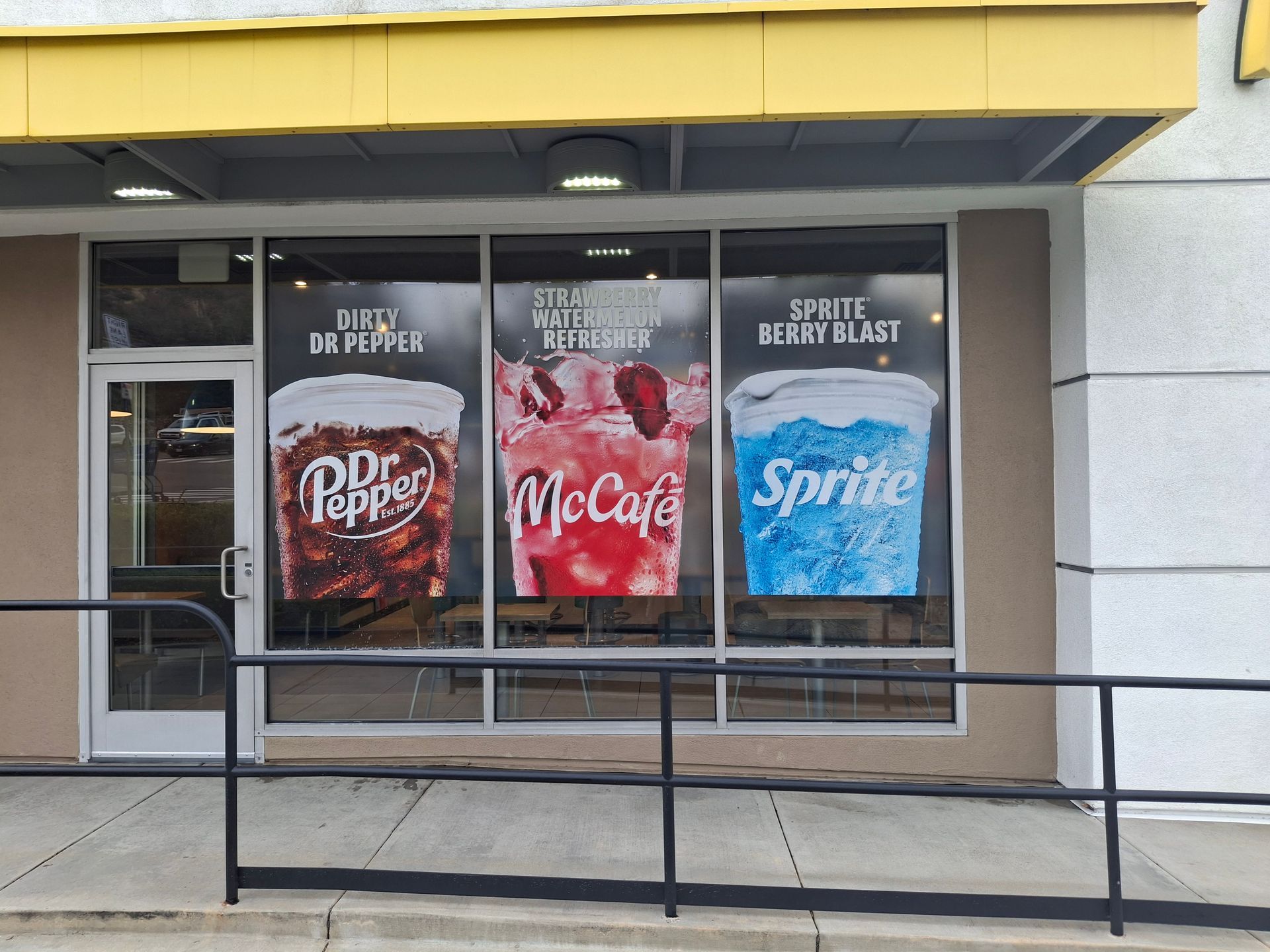 Storefront with Dr Pepper, Coca-Cola, and Sprite ads behind a black railing