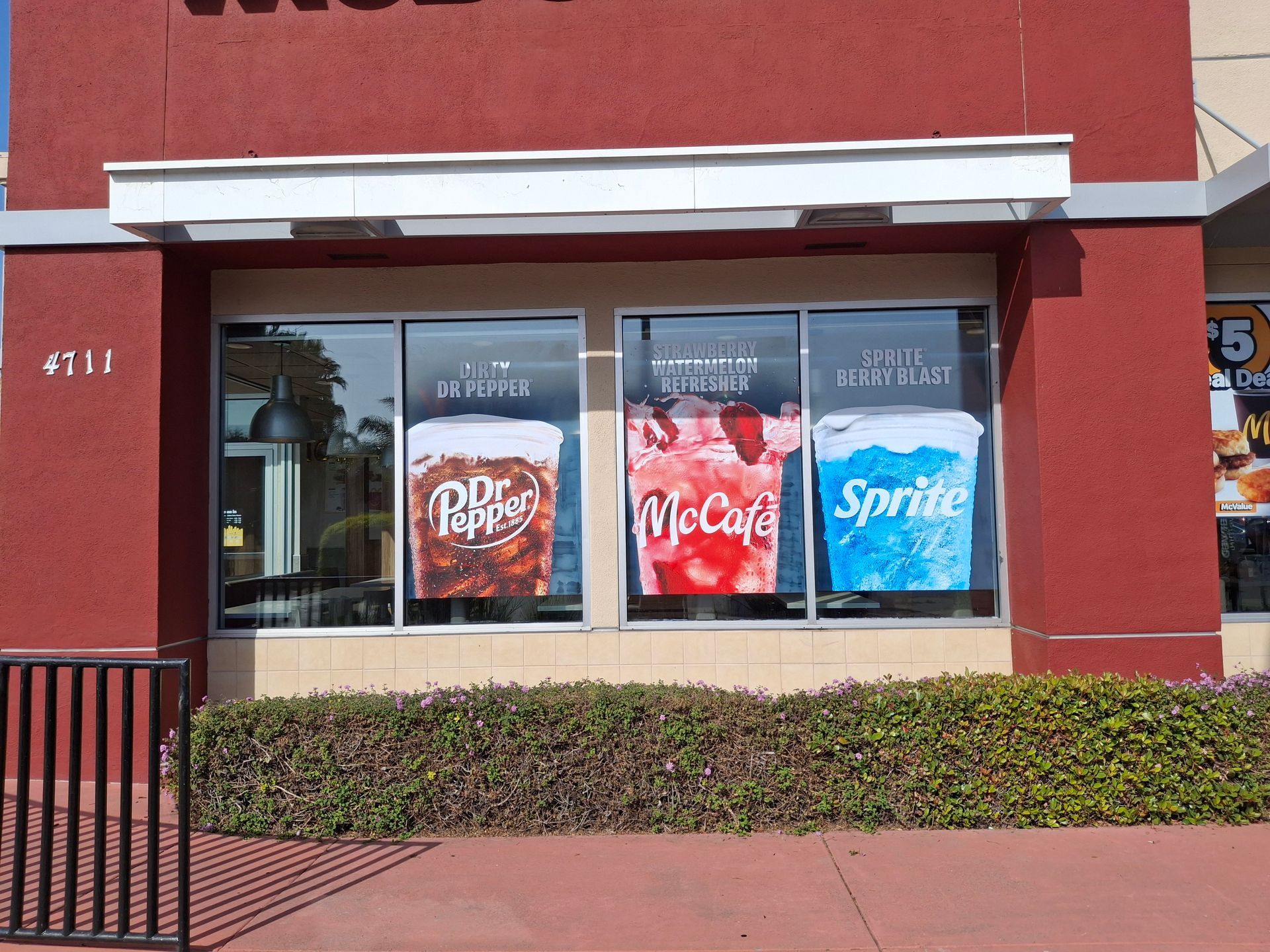 Storefront window with Dr Pepper, McCafé, and Sprite promotional signs on a red building