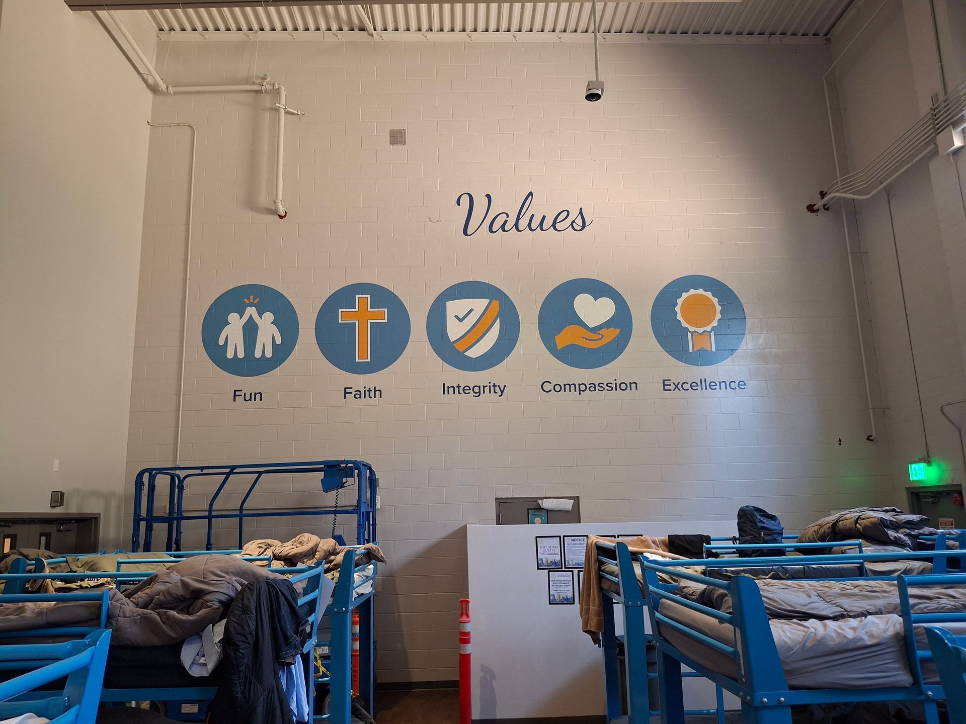 Gym interior with “Values” wall art and five blue circular icons above workout equipment