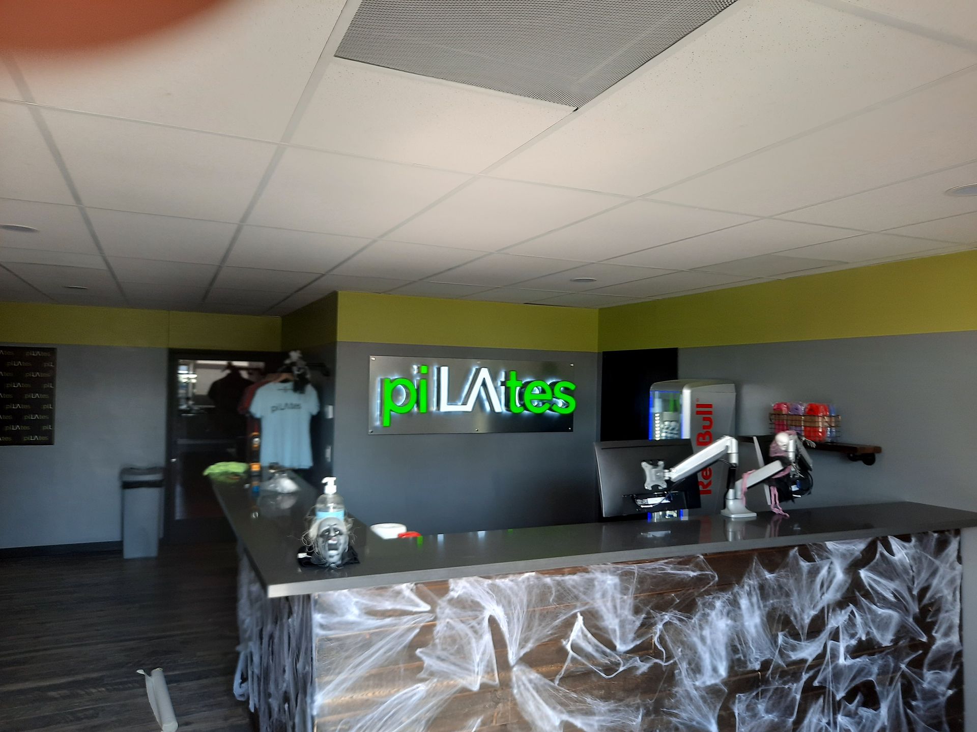 Empty Pilates studio with black reception desk, green logo, and plastic-covered front counter