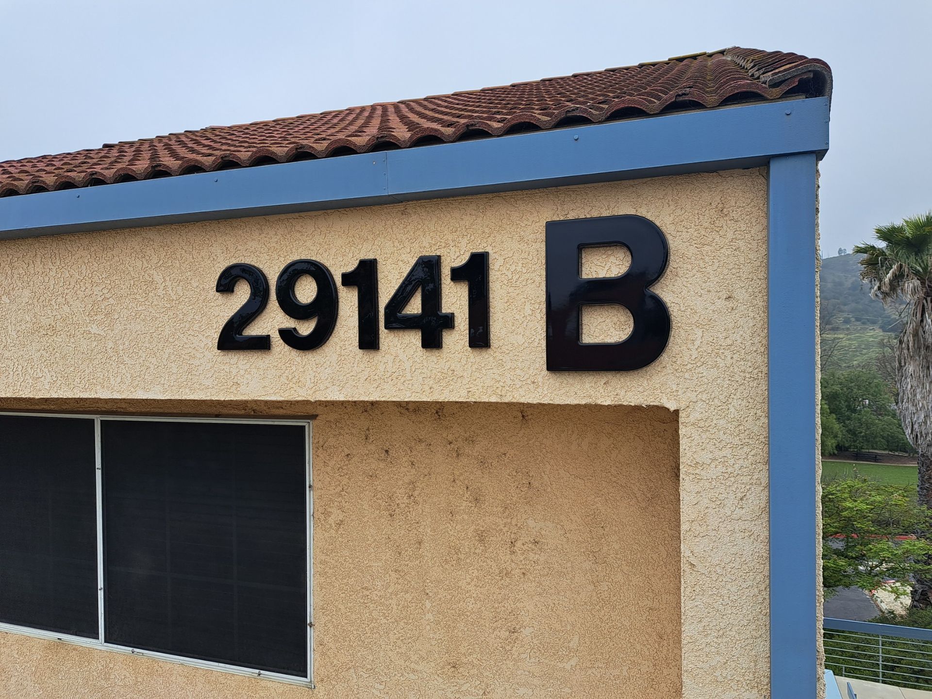 Building facade with address number 29141 and a large black letter B under a blue roof trim.