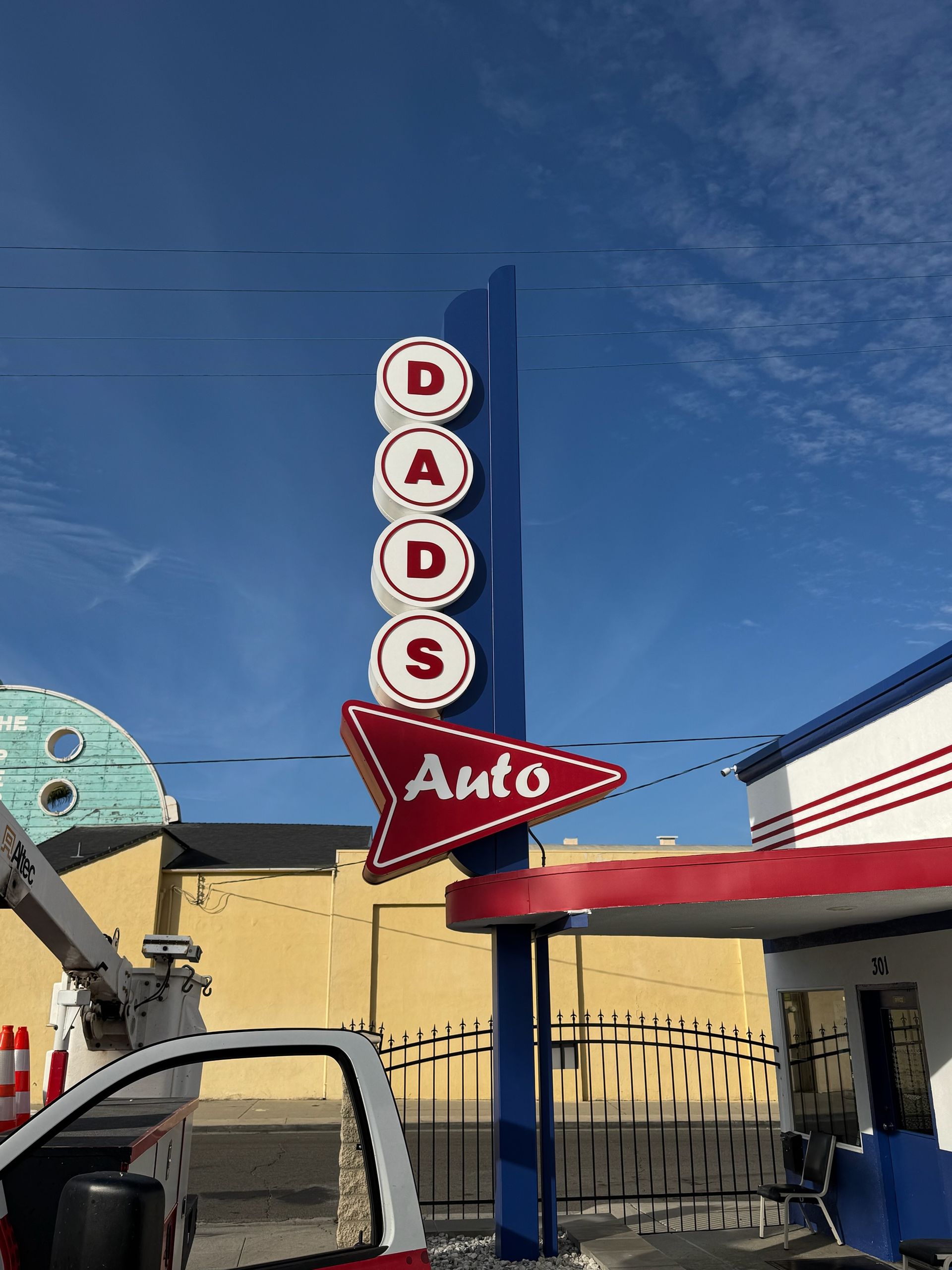 Retro DADS Auto sign with red star on a blue pole against a clear sky