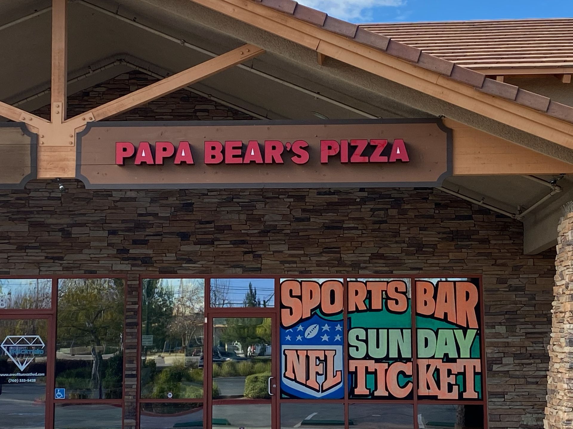 Papa Bear’s Pizza storefront with sports bar signs and red awning on a stone facade