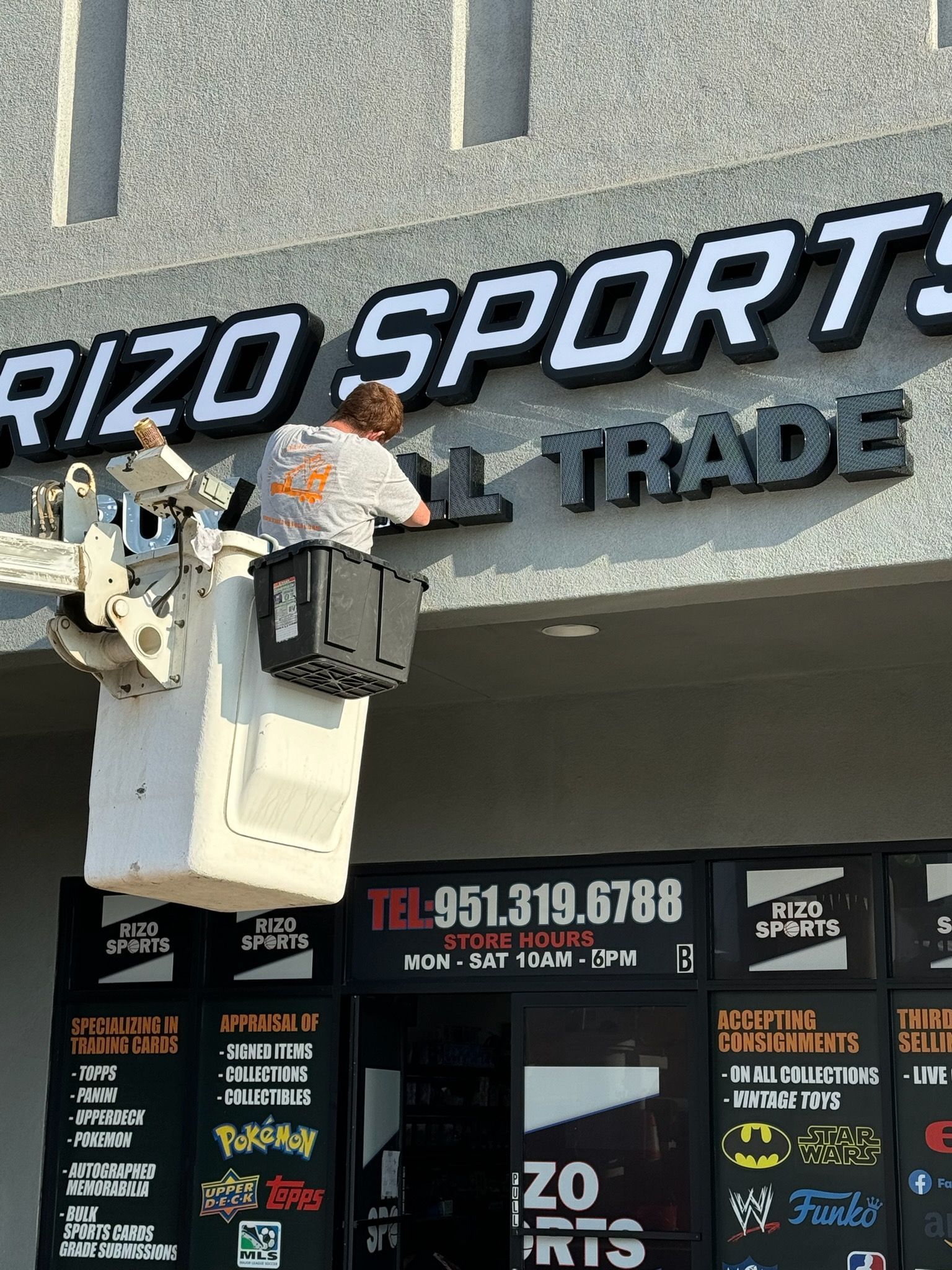 Workers installing signage on the storefront of a sports and trade shop