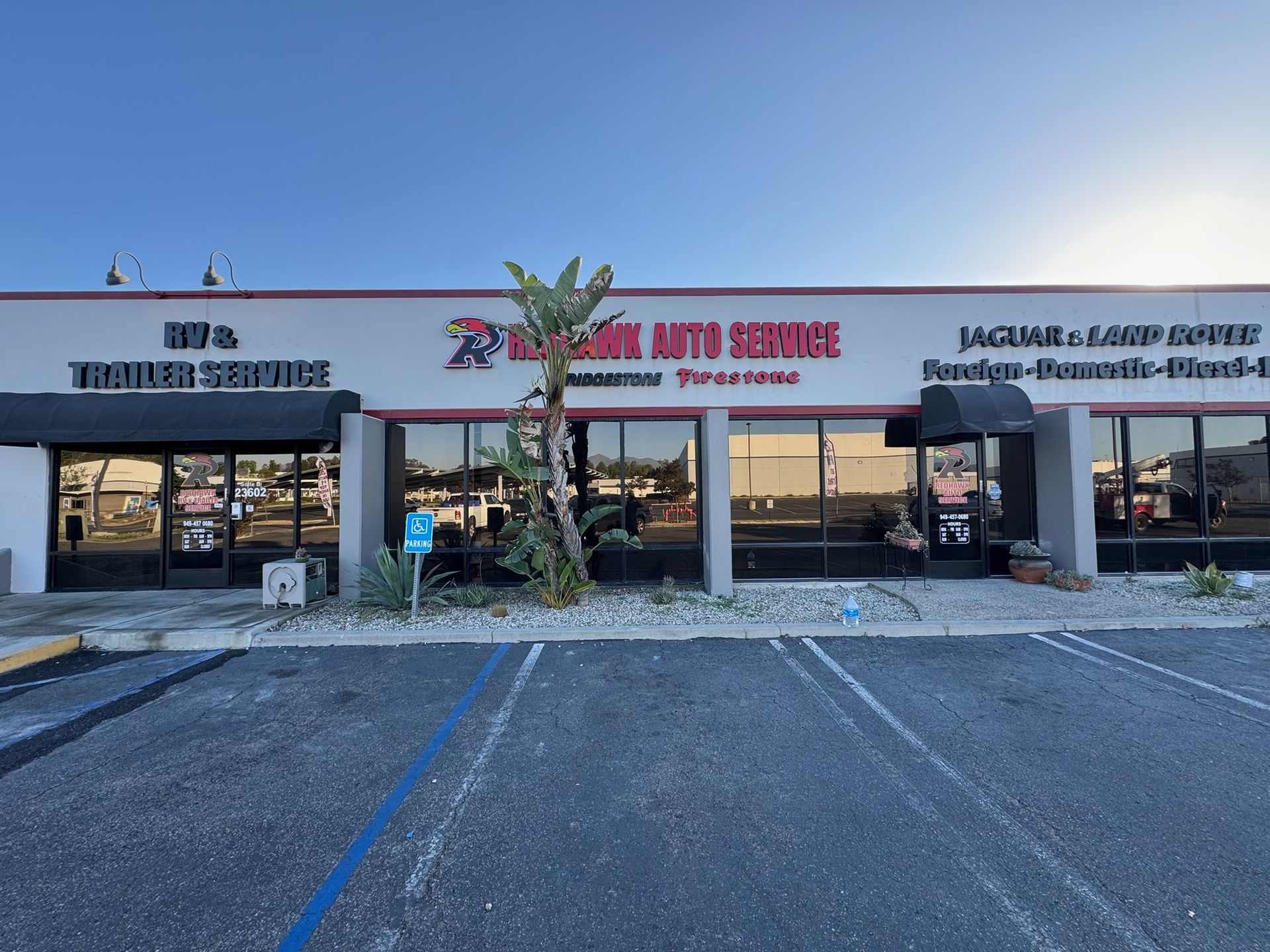 Strip mall auto service storefronts with parking lot at sunset