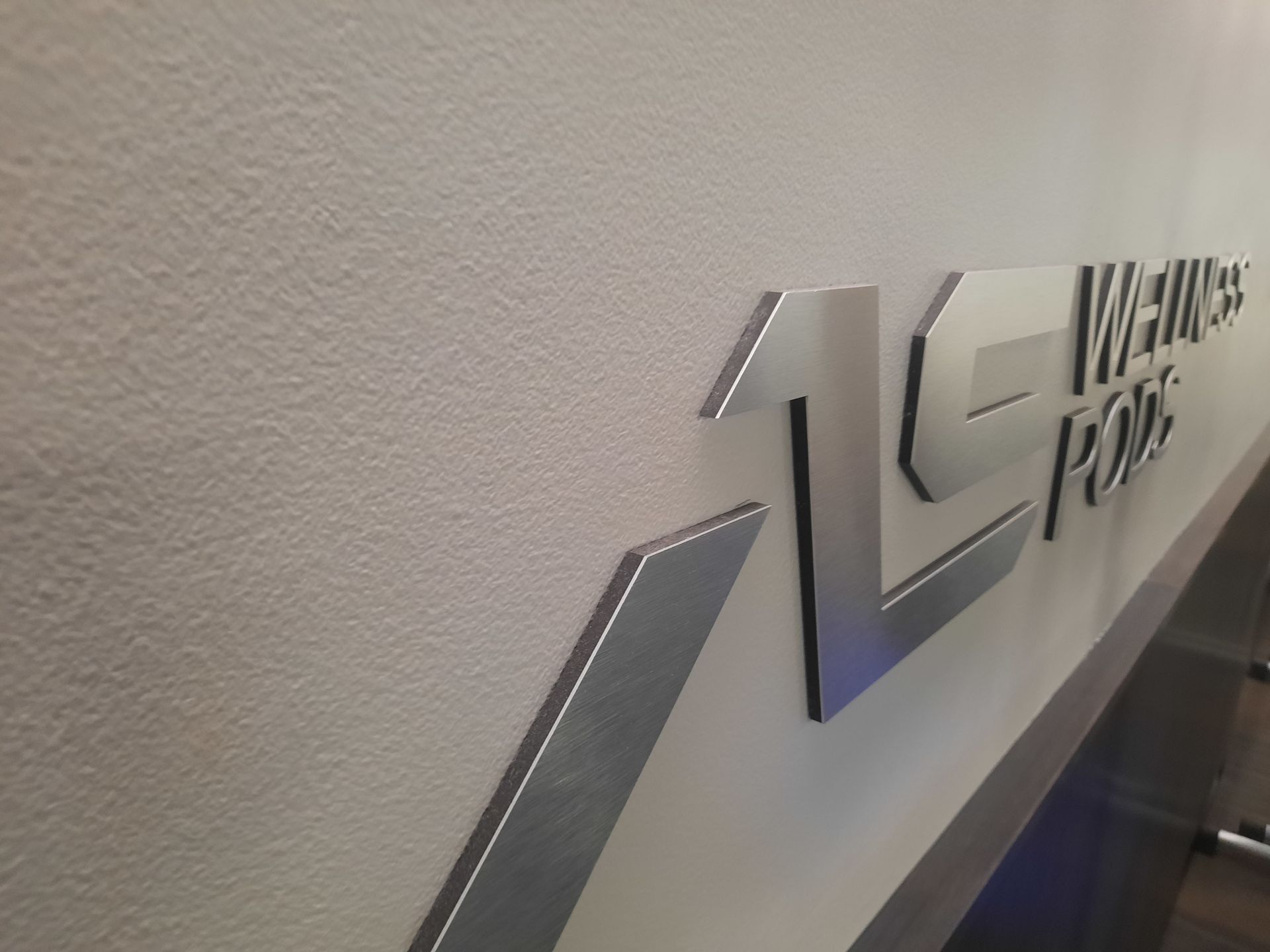 Metallic 13WHEELS PARK sign on a beige wall, viewed at an angle