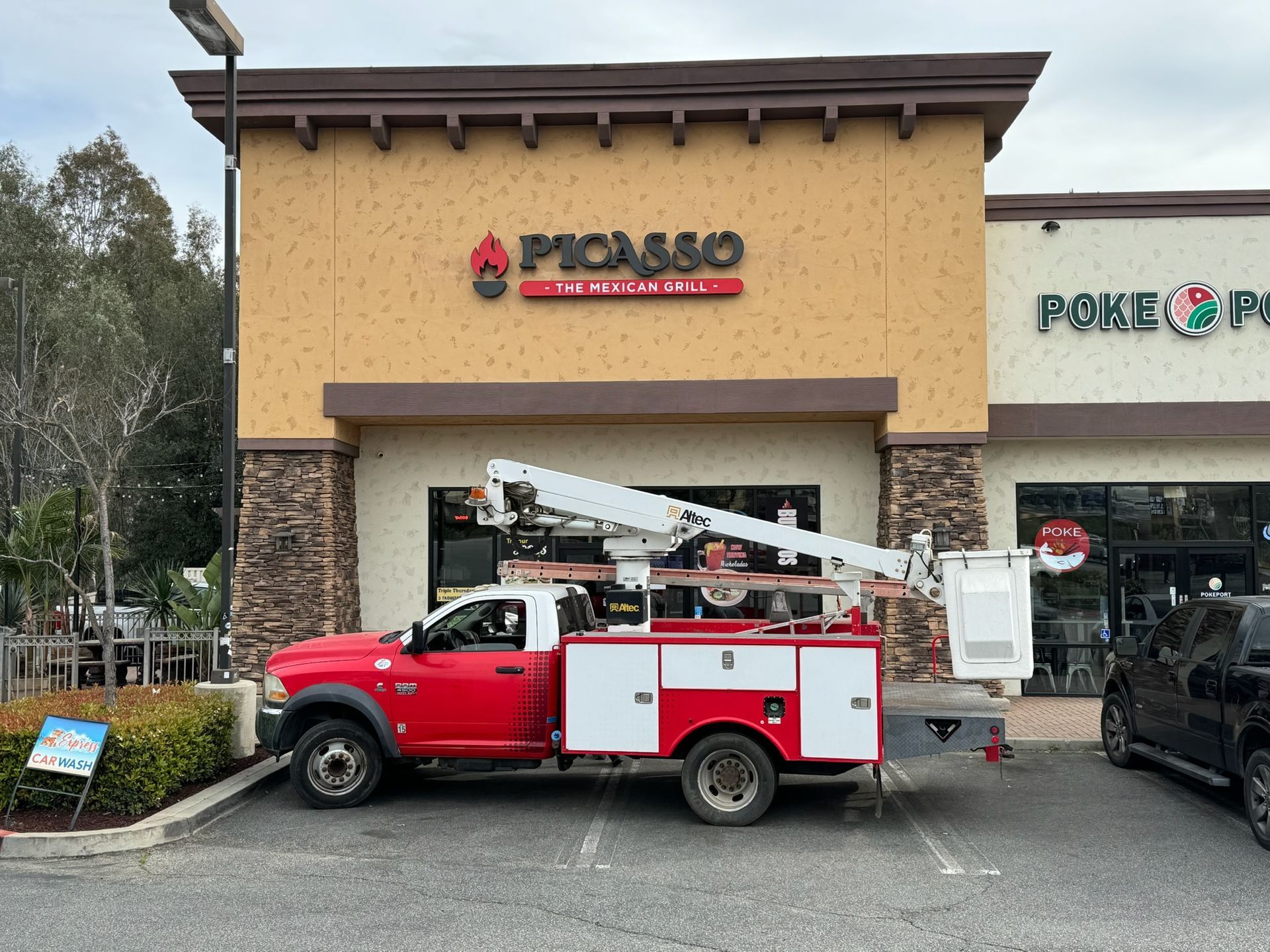 Red fire truck with ladder parked outside a restaurant building with a partially visible sign.