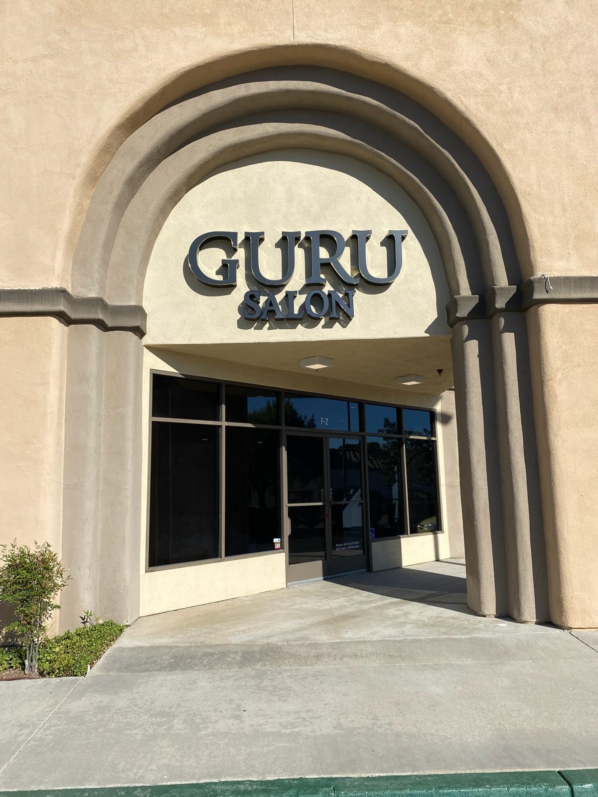 GURU SALON storefront with arched beige facade and glass entrance