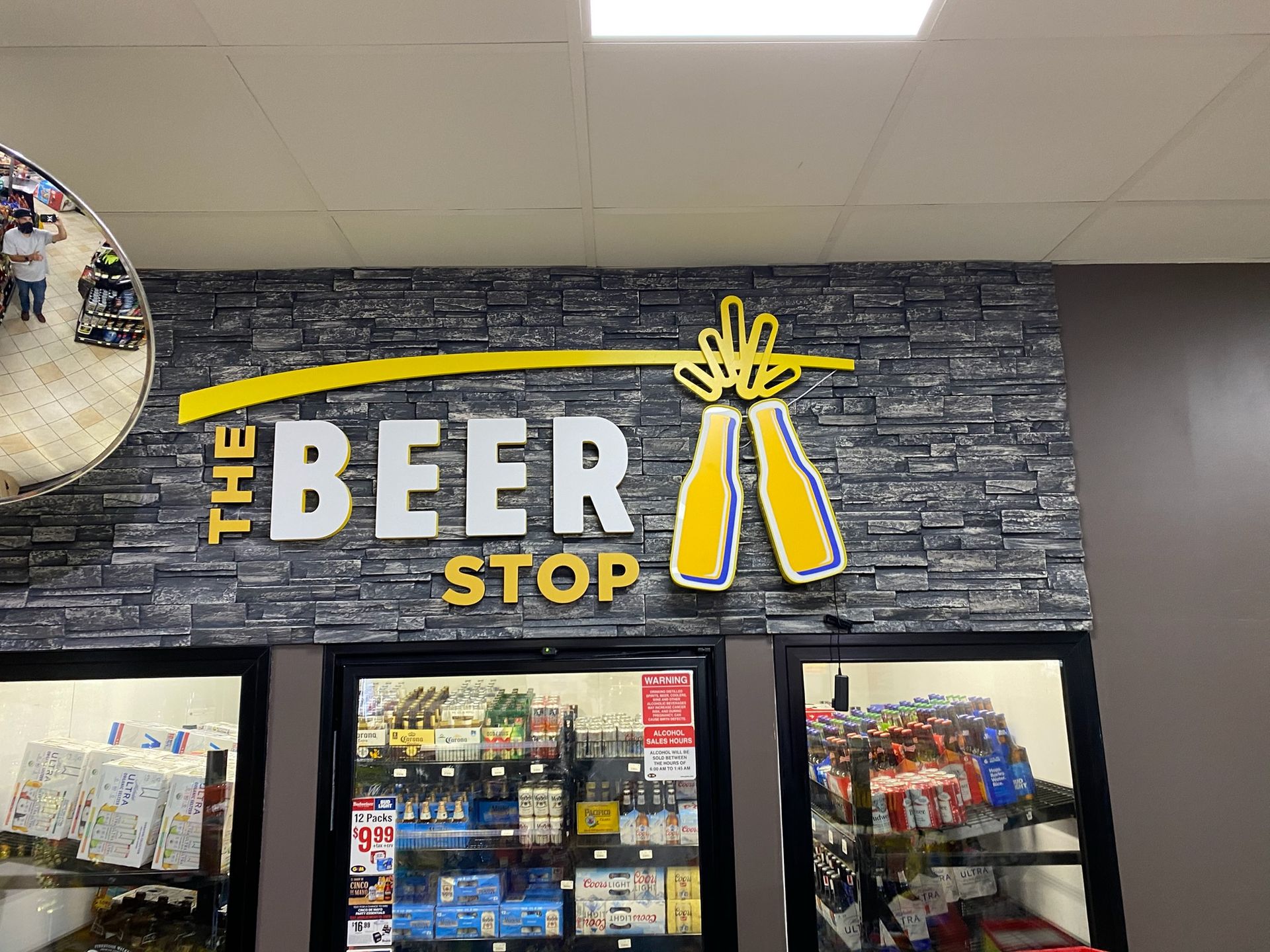 Beer Stop storefront sign in white and yellow on a dark brick wall above refrigerated display cases